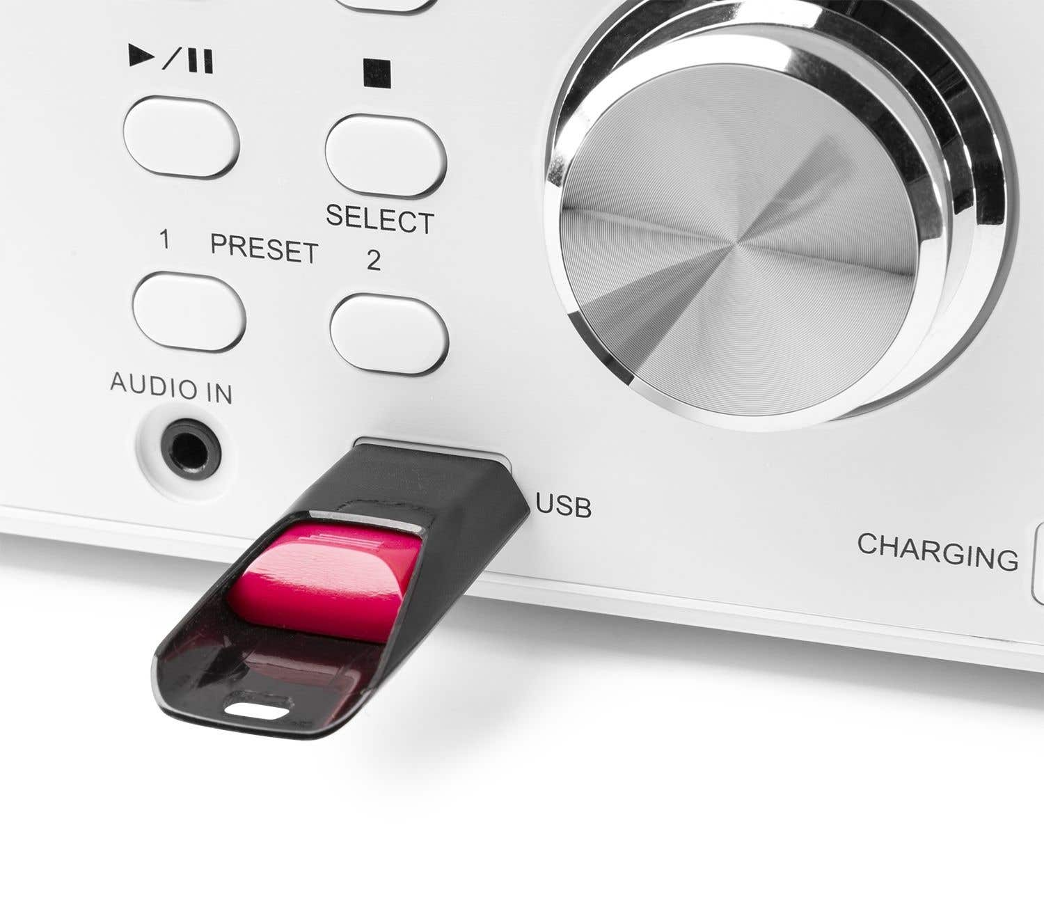 Weißes Stereoanlage mit Knöpfen, einem USB-Anschluss mit rosa Einsatz und einem großen silbernen Drehknopf. Das System ist beschriftet.