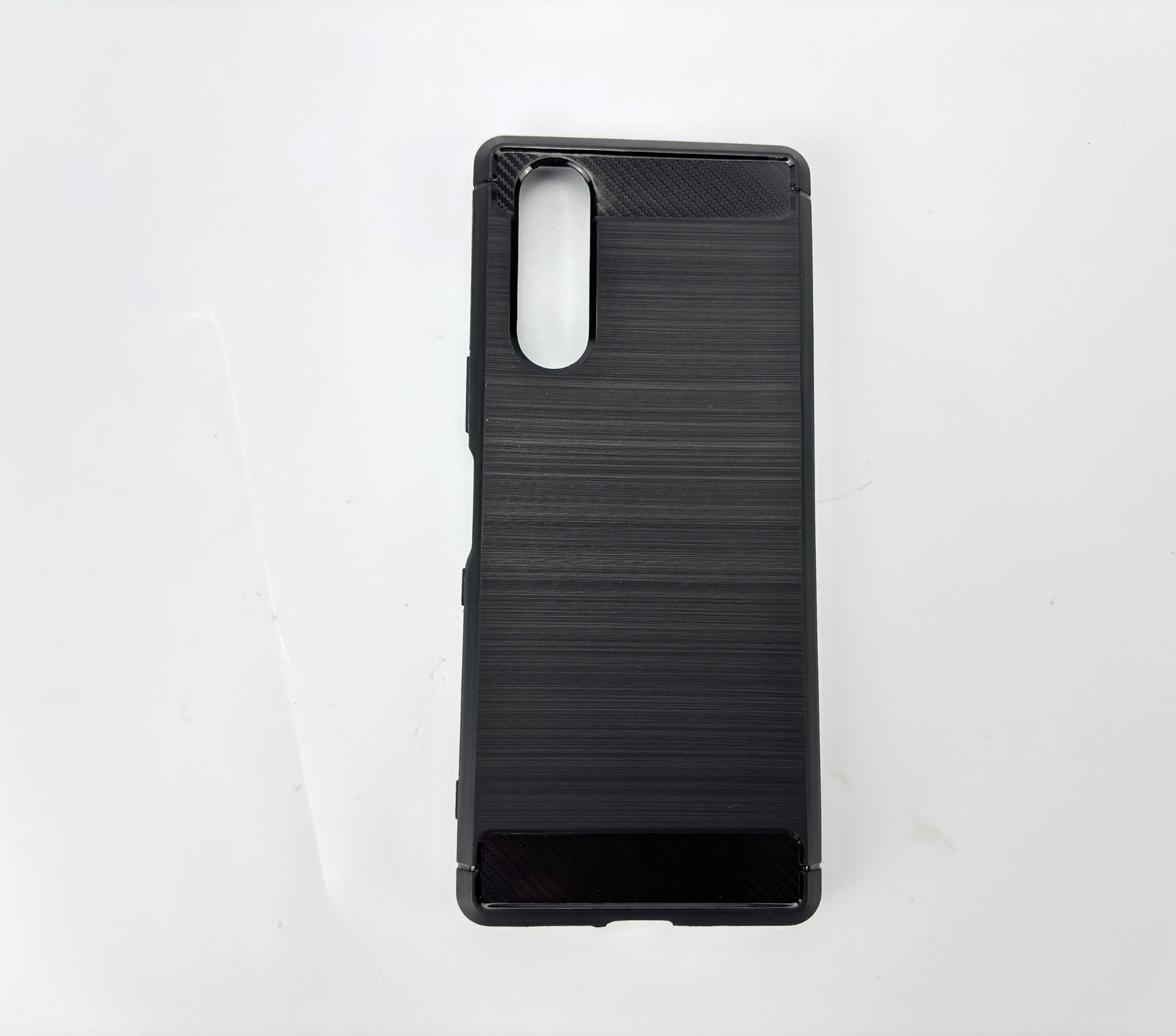 Custodia nera per telefono con retro strutturato, ritaglio per fotocamera e accento in fibra di carbonio su superficie bianca.