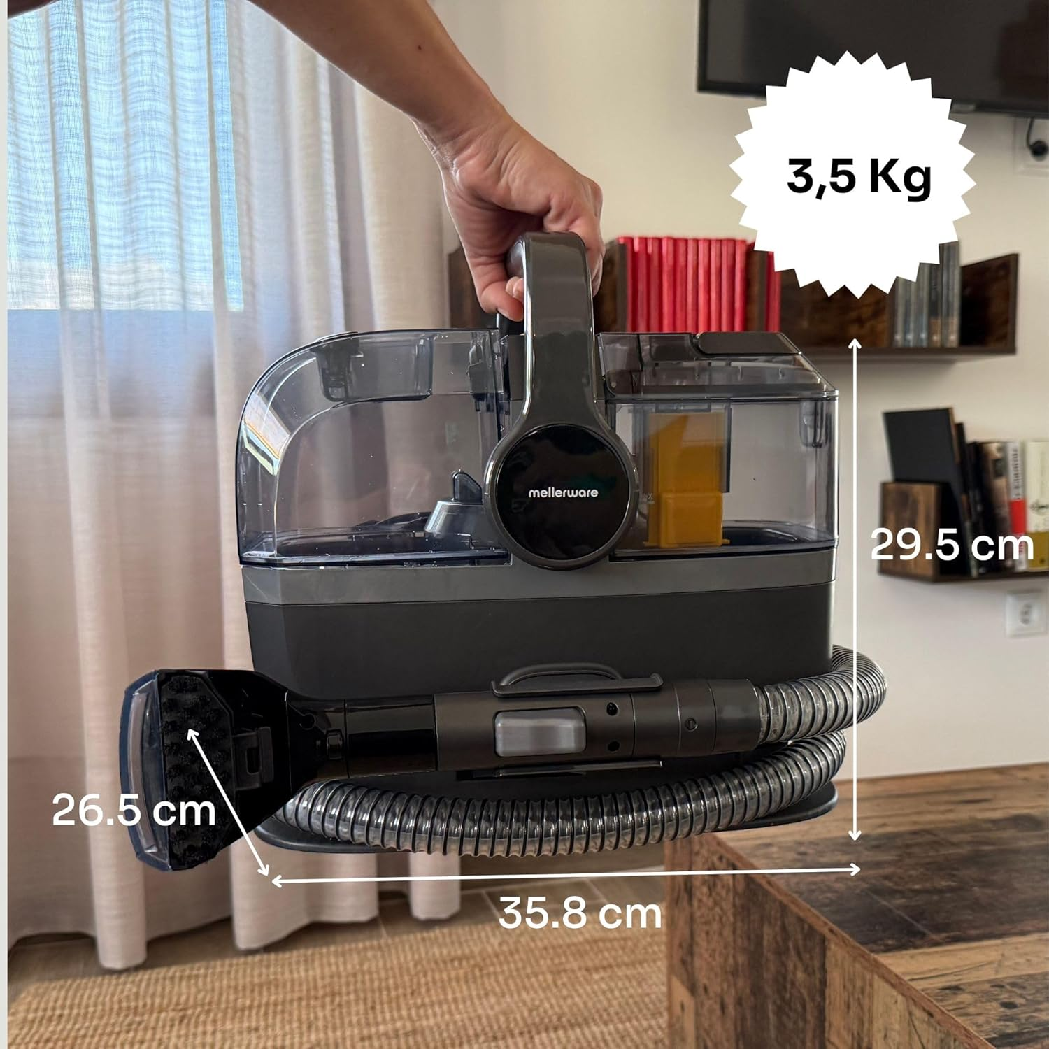 Una persona tiene in mano una pulitrice per tappeti Mellerware grigia e nera. Sono indicate dimensioni e peso. Lo sfondo mostra mensole e una TV.