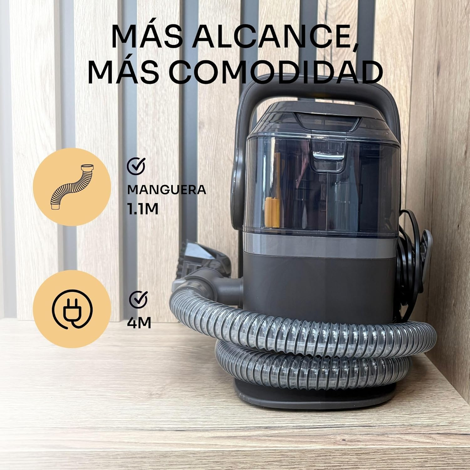 Un aspirapolvere nero e grigio con un tubo flessibile e un cavo di alimentazione su una superficie di legno. Testo: 'Più portata, più comodità'.