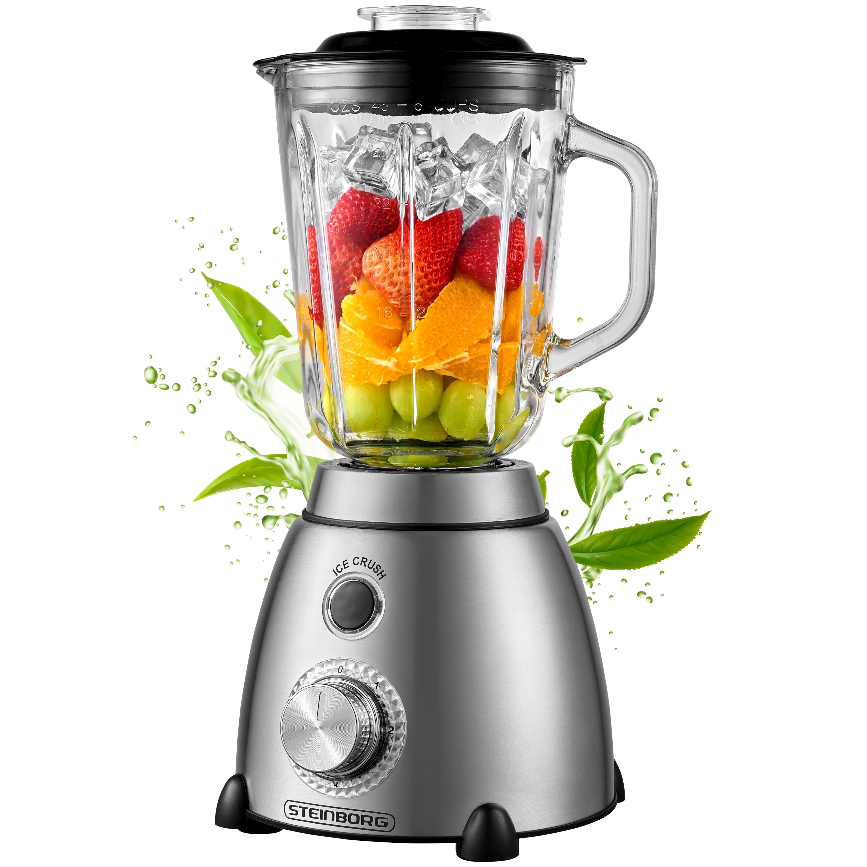 Ein Mixer mit Erdbeeren, Orangen, Trauben und Eiswürfeln. Grüne Flüssigkeit und Blätter spritzen heraus.