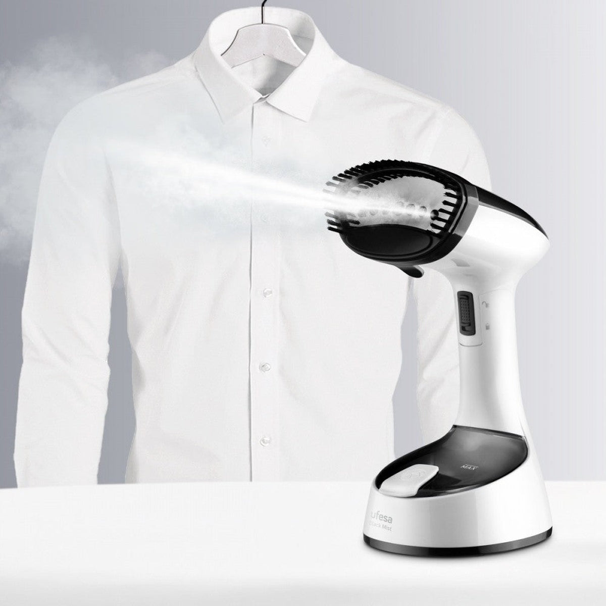 Una camisa blanca en una percha se está planchando con vapor por un vaporizador blanco y negro. El vapor se dirige a la camisa.
