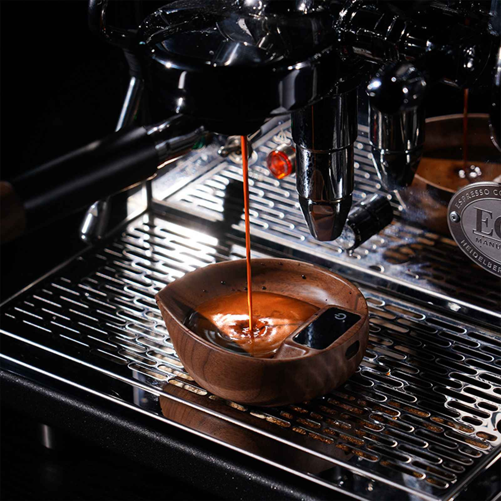Espressomaschine, die Kaffee in eine Holzschale abgibt. Nahaufnahme, die den Kaffeestrom und Details der Maschine zeigt.