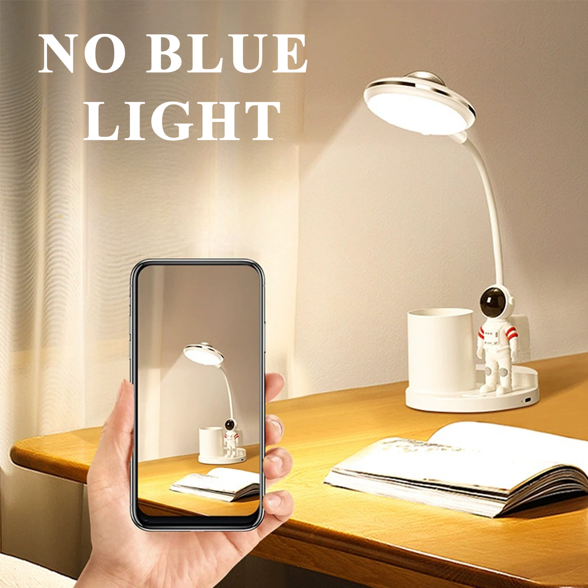 Eine Hand hält ein Telefon mit einer Schreibtischlampe mit einem Astronauten. Eine echte Schreibtischlampe mit Astronautenfigur steht auf dem Tisch.