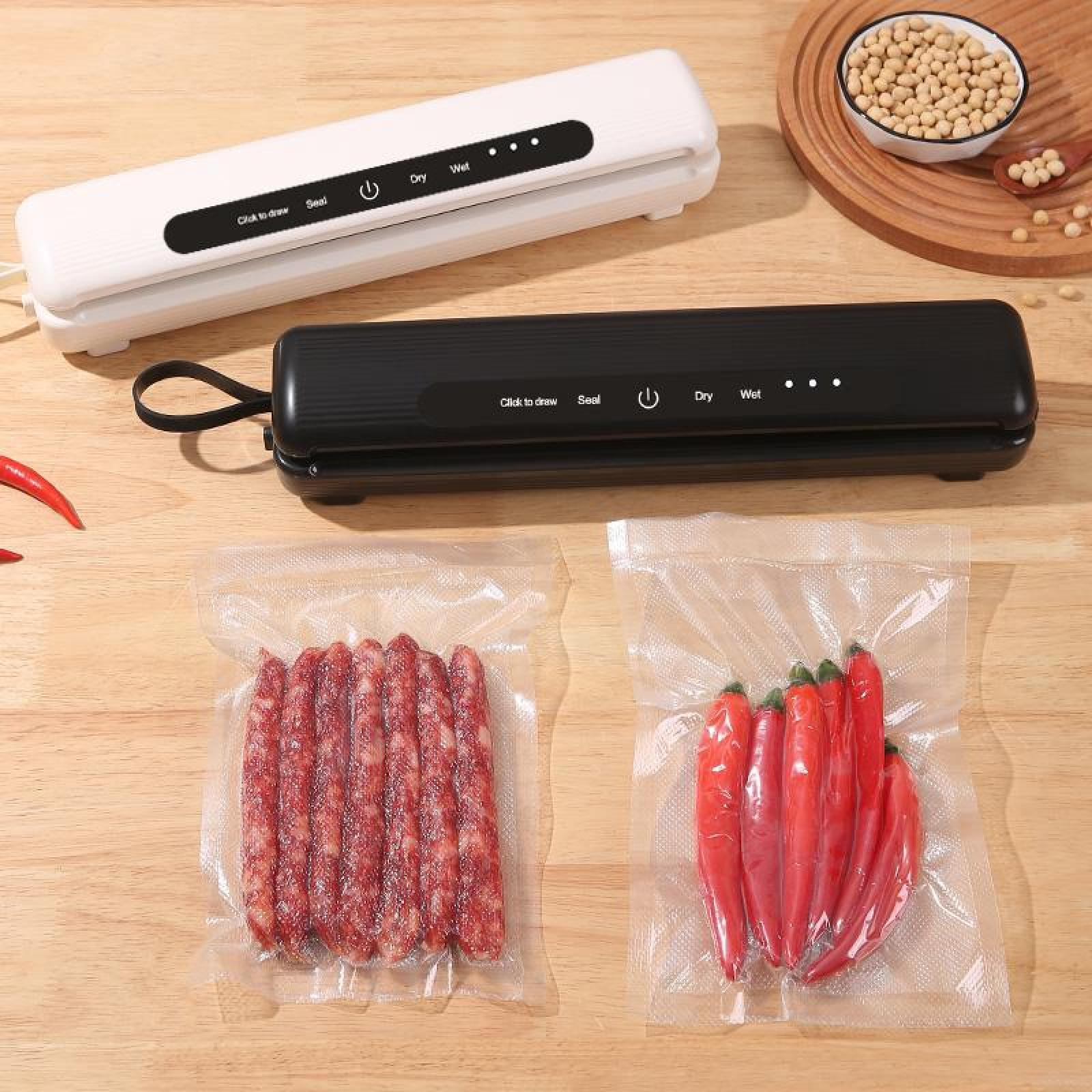 Zwei Vakuumiergeräte, weiß und schwarz, über versiegelten Beuteln mit Wurst und roten Paprika auf einer Holzoberfläche.