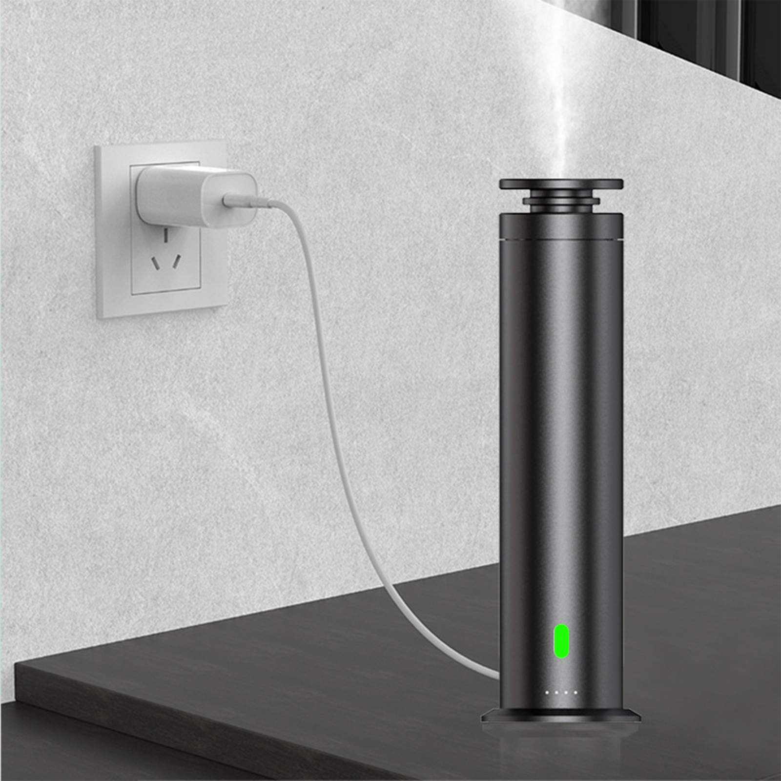 Ein schwarzer Diffusor ist mit einem weißen Kabel und Ladegerät angeschlossen. Eine weiße Steckdose befindet sich an der Wand, und Dampf tritt aus.