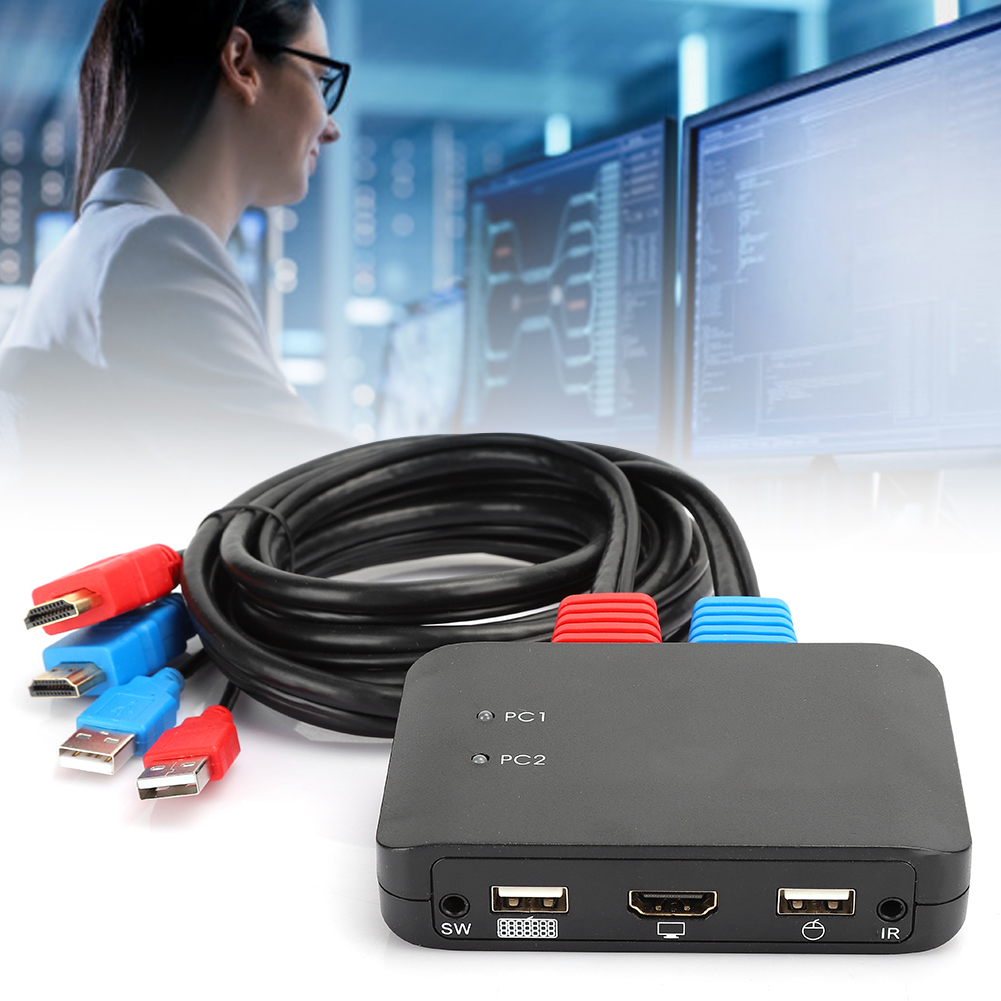 Eine Frau mit Brille betrachtet Monitore. Schwarzes Kabel und eine Switch-Box sind im Vordergrund. Kabel haben rote und blaue Stecker.