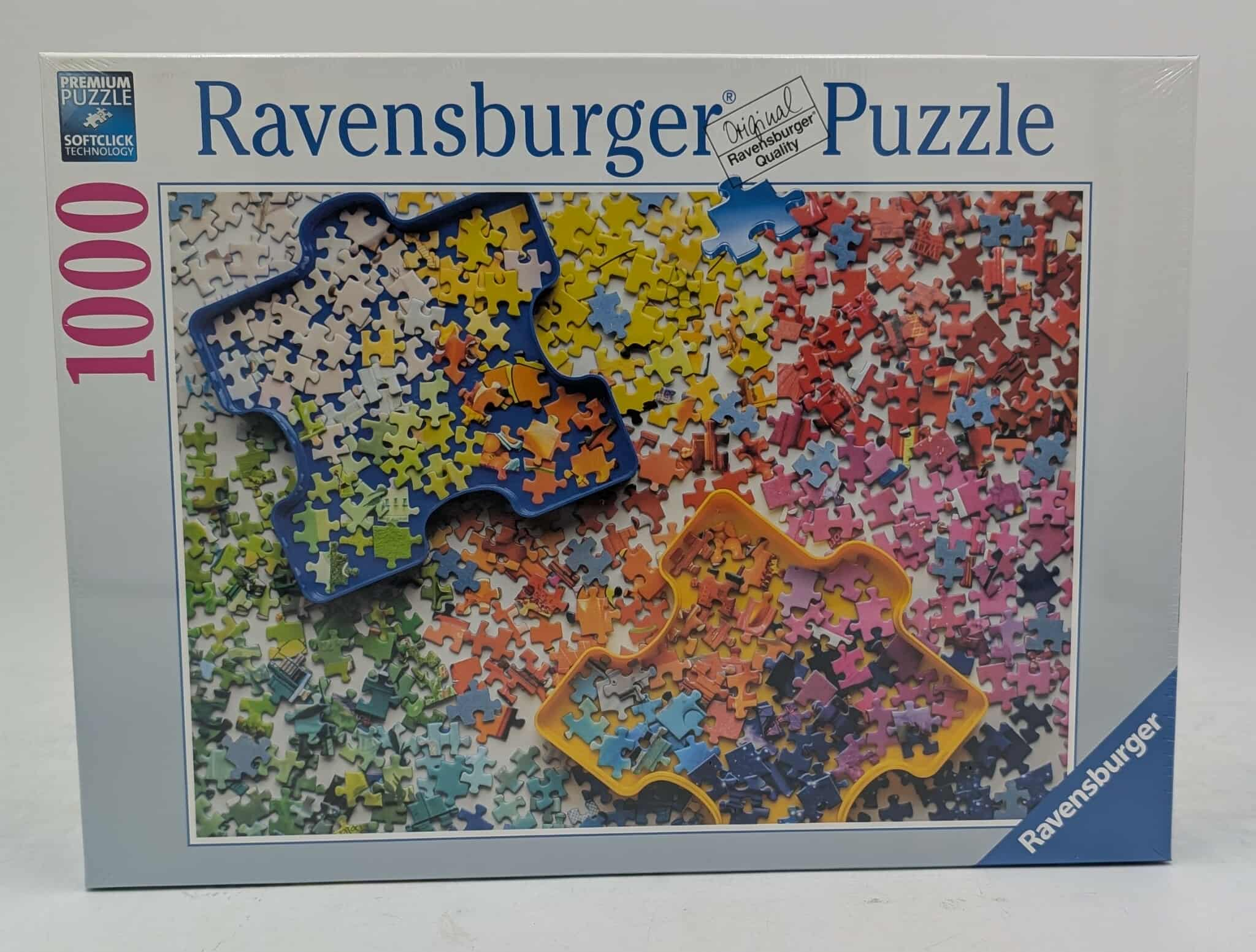 Ravensburger 1000-teilige Puzzlebox. Puzzleteile in verschiedenen Farben, mit zwei geformten Tabletts. Die Box ist weiß.