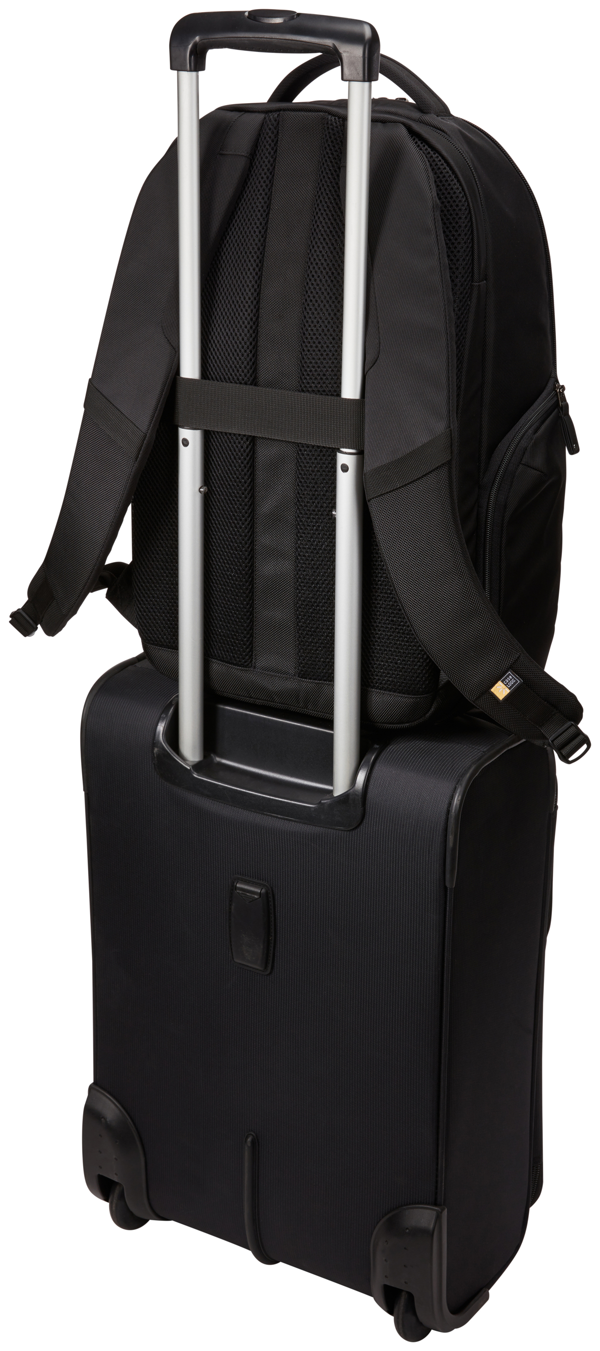 Ein schwarzer Rucksack steht auf einem schwarzen Rollkoffer. Der Koffergriff ist ausgezogen. Der Hintergrund ist weiß.