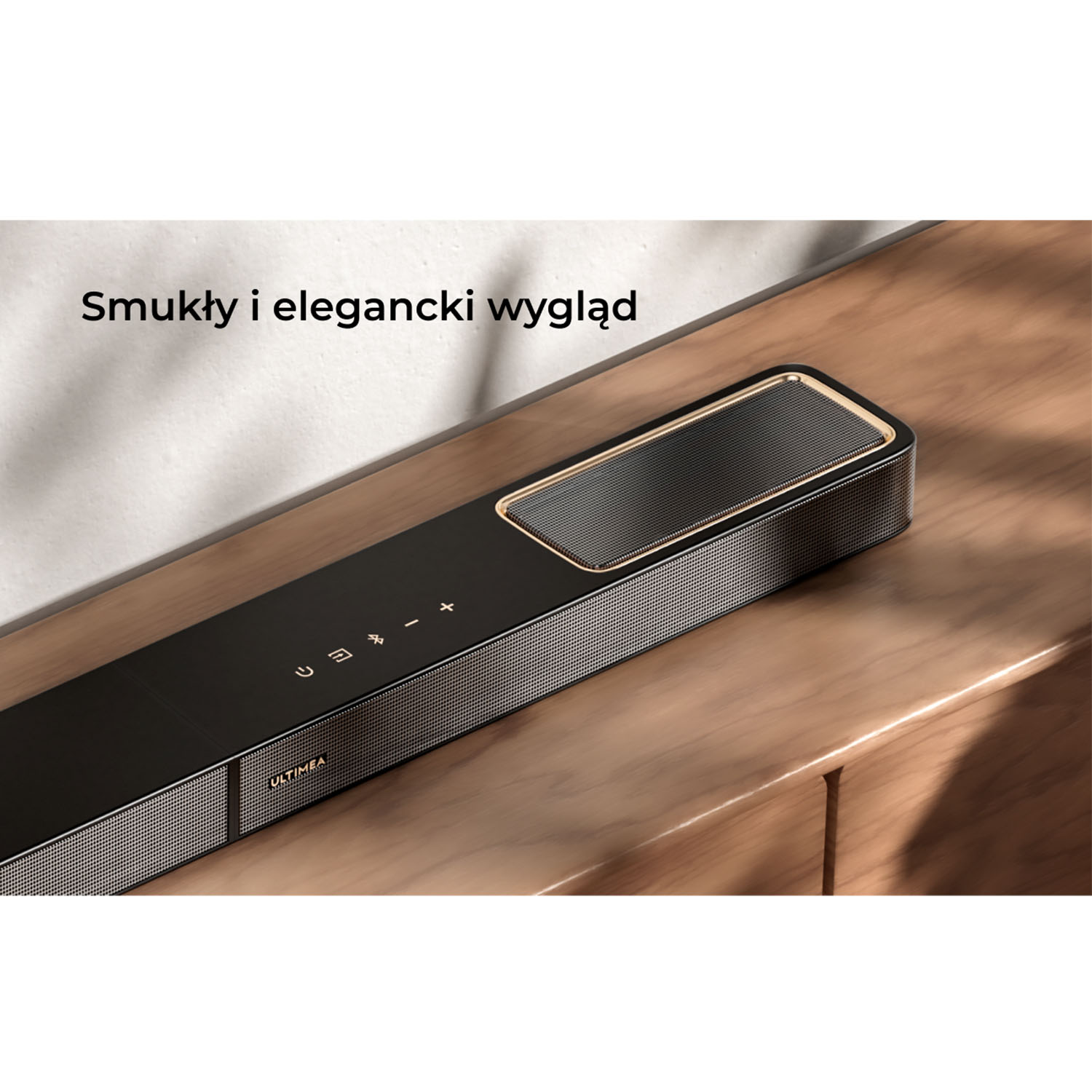 Czarny soundbar ze złotymi akcentami leży na drewnianej powierzchni. Soundbar ma siatkową kratkę i symbole sterowania. Marka to Ultimea.
