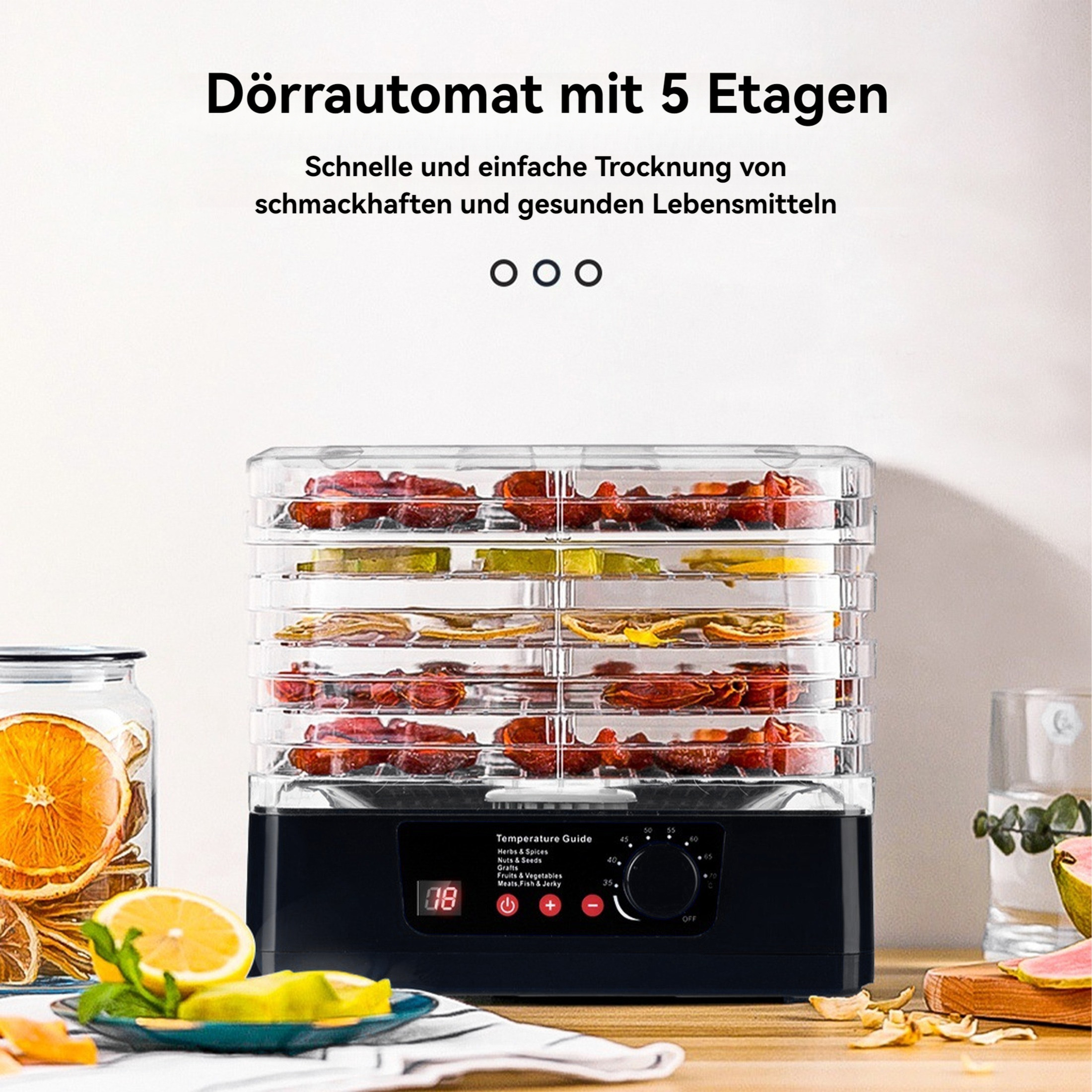 Ein Dörrautomat mit fünf Tabletts, gefüllt mit Früchten. Ein Glas getrocknete Orangen und Zitronenscheiben stehen auf dem Tisch.