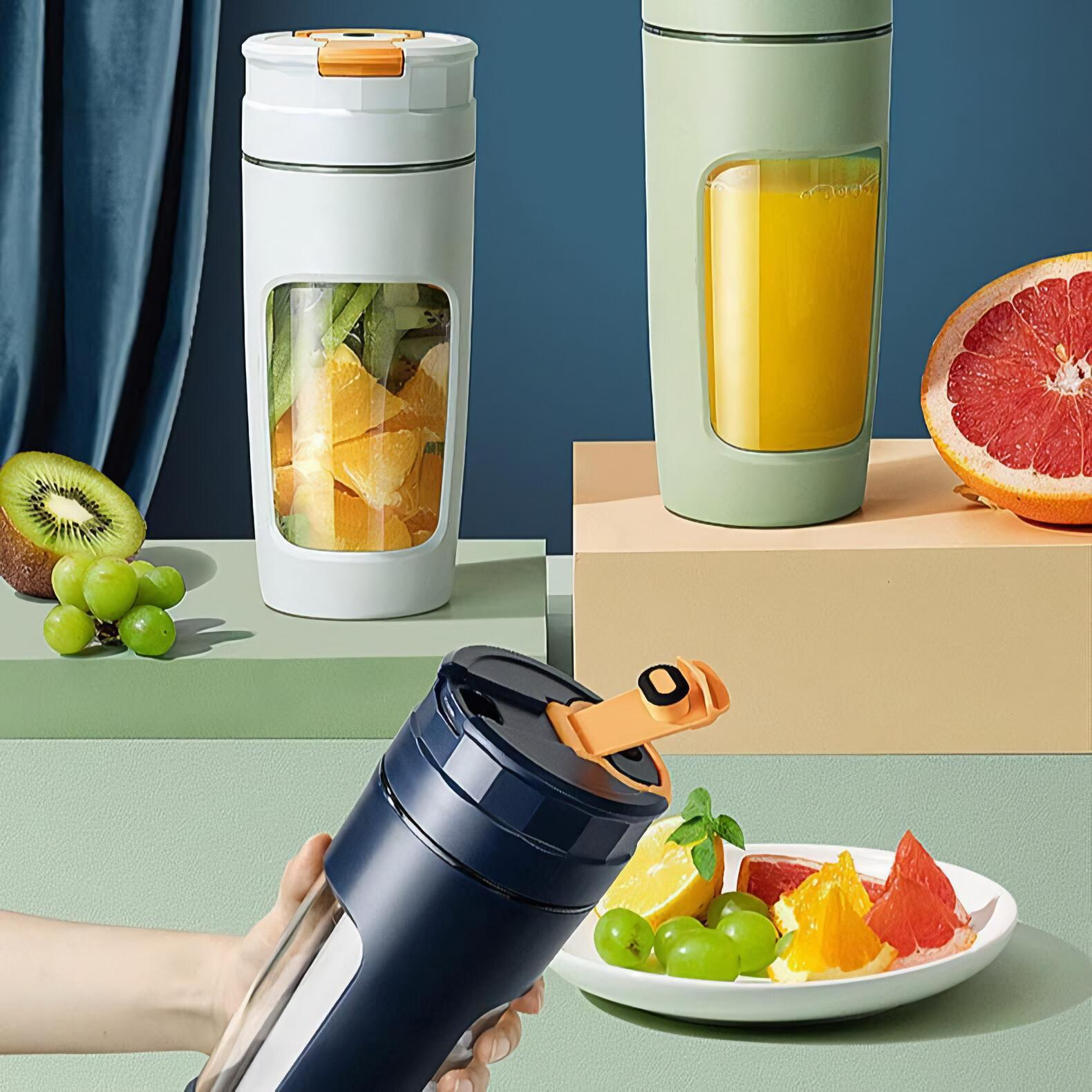 Mixer mit Früchten. Eine Hand hält einen. Andere auf einer Oberfläche. Früchte sind Kiwi, Trauben, Grapefruit und Orangen.