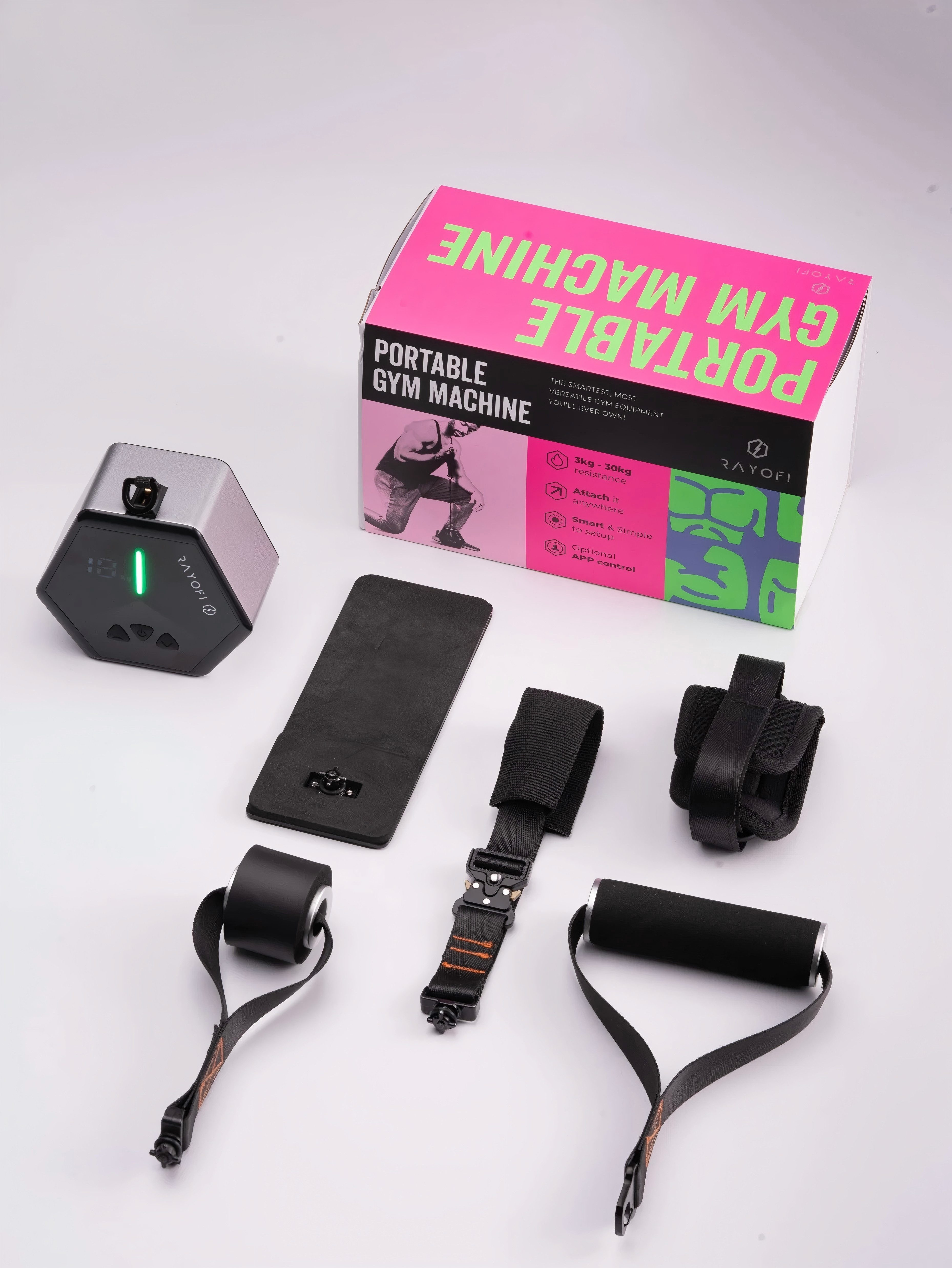 Ein tragbares Fitnessgerät mit Box, Basis und Gurten. Die Box ist pink und grün. Das Set beinhaltet ein digitales Gerät.