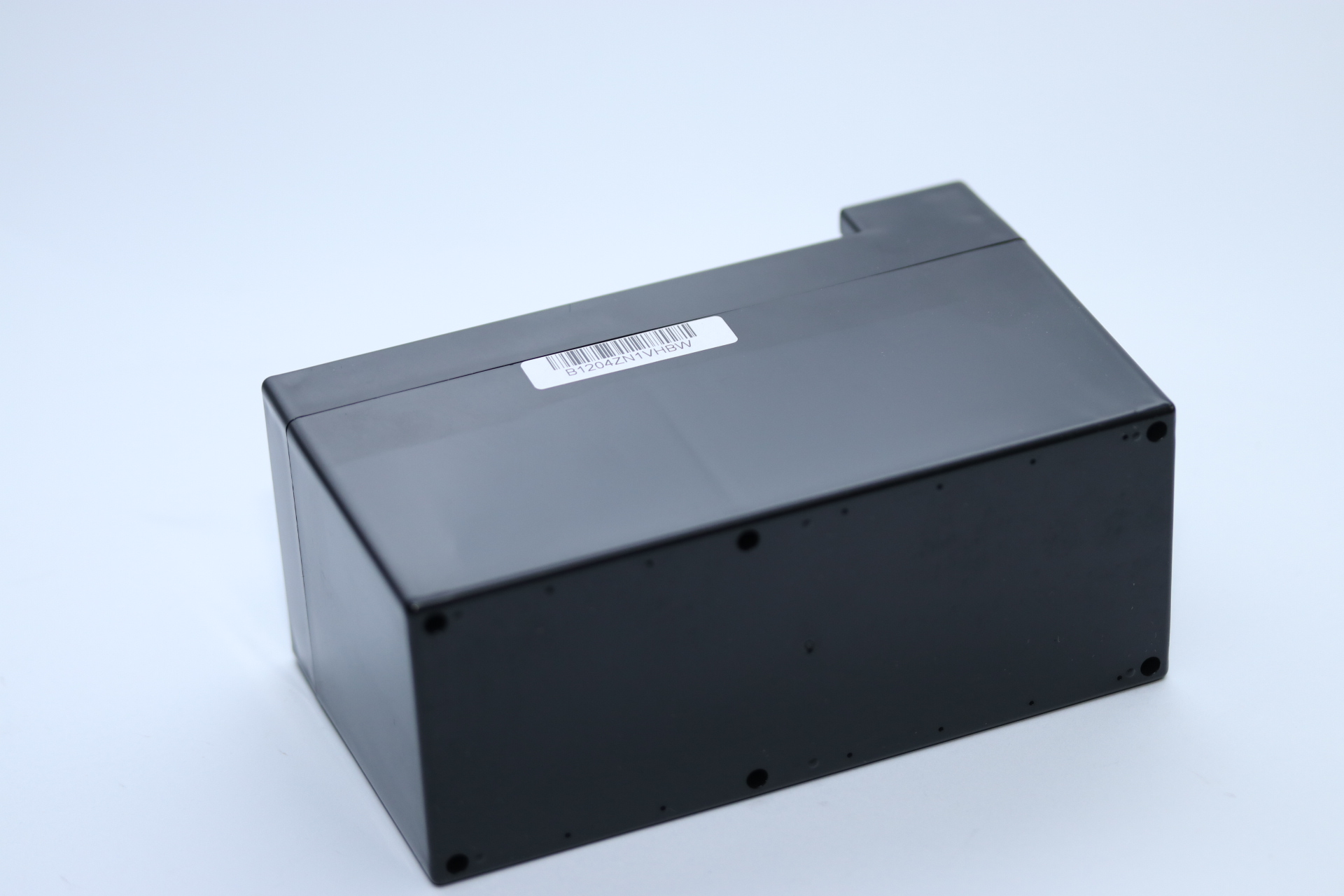 Eine schwarze rechteckige Box mit einem Aufkleber mit der Aufschrift B1204ZN1VHBW auf weißem Untergrund. Die Box ist leicht angewinkelt.
