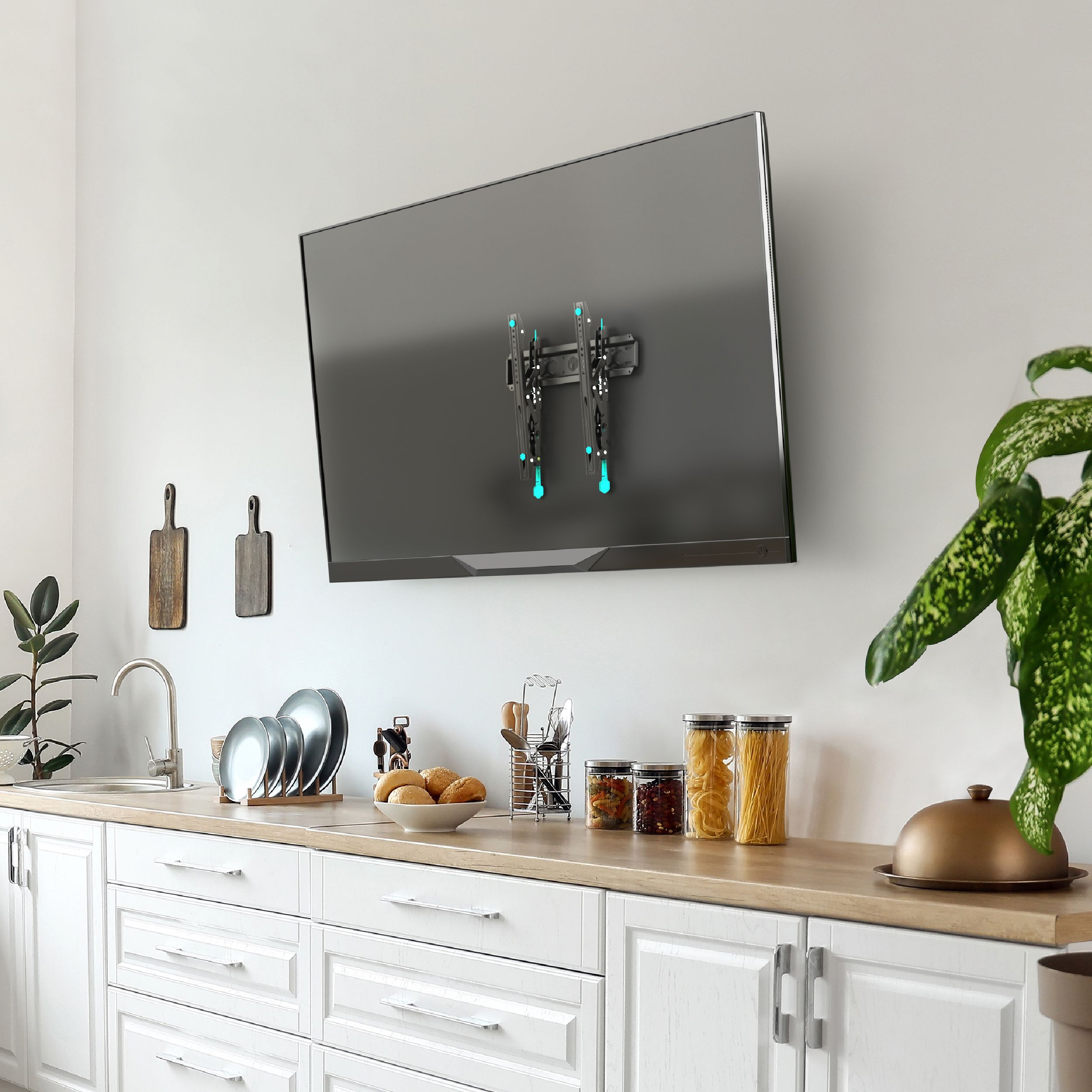 Scena kuchenna z telewizorem na ścianie, blatem z jedzeniem, zlewem i roślinami. Widoczny uchwyt TV.