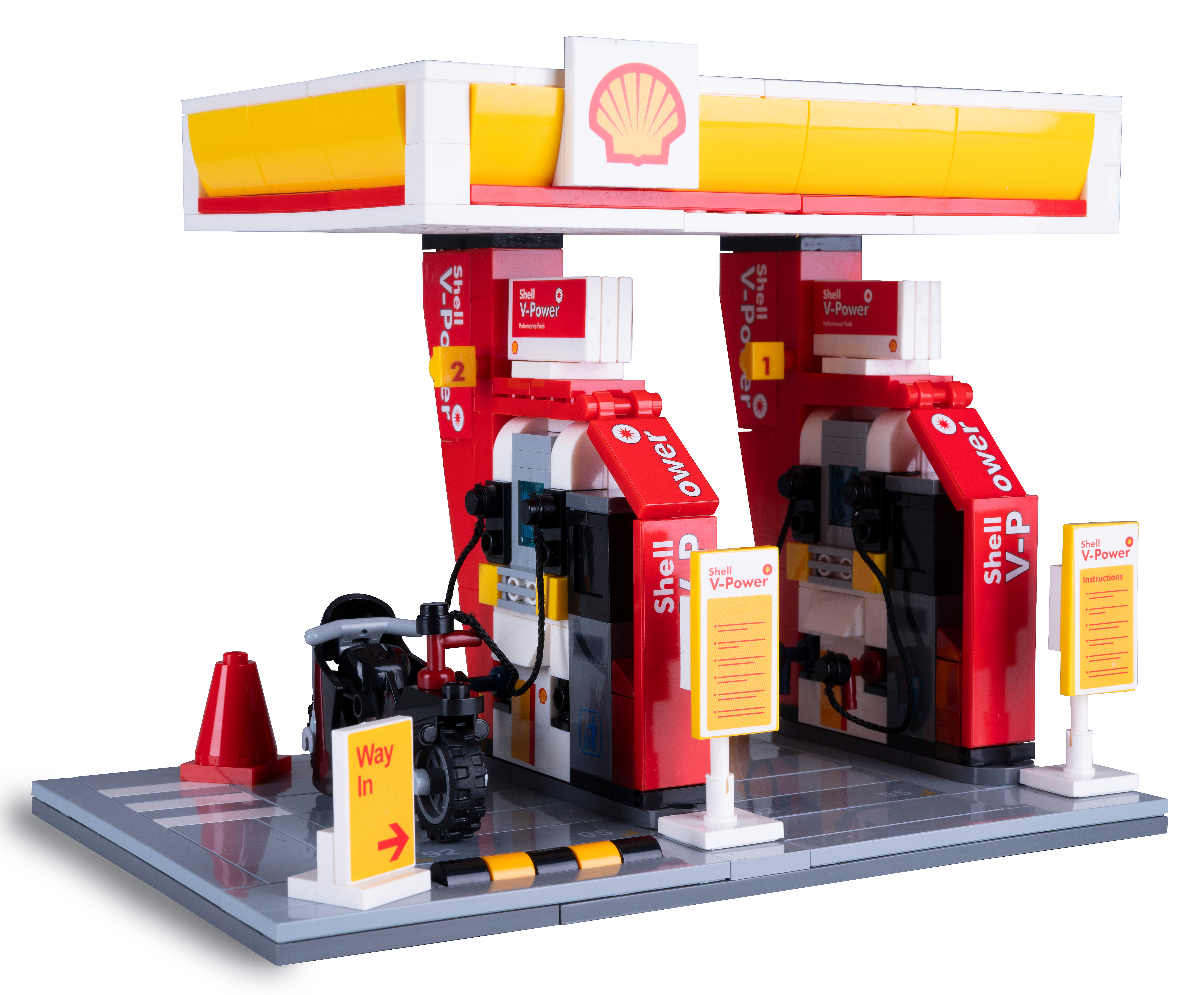 Ein Lego Shell-Tankstellenmodell. Verfügt über zwei rot-gelbe Zapfsäulen mit Schildern, ein Motorrad und einen roten Kegel.