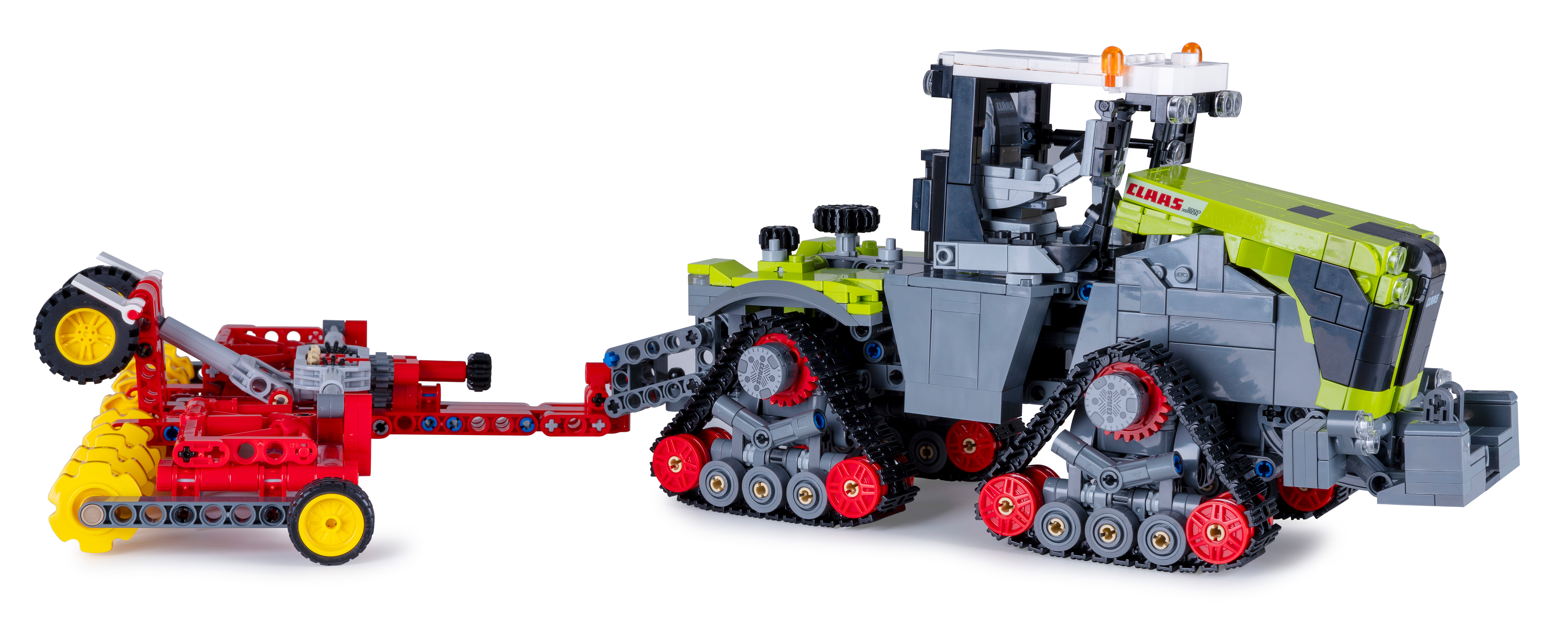 Ein Lego Claas Xerion Traktormodell mit rotem Anhänger. Der Traktor ist grau, grün und schwarz. Der Anhänger ist rot und gelb.