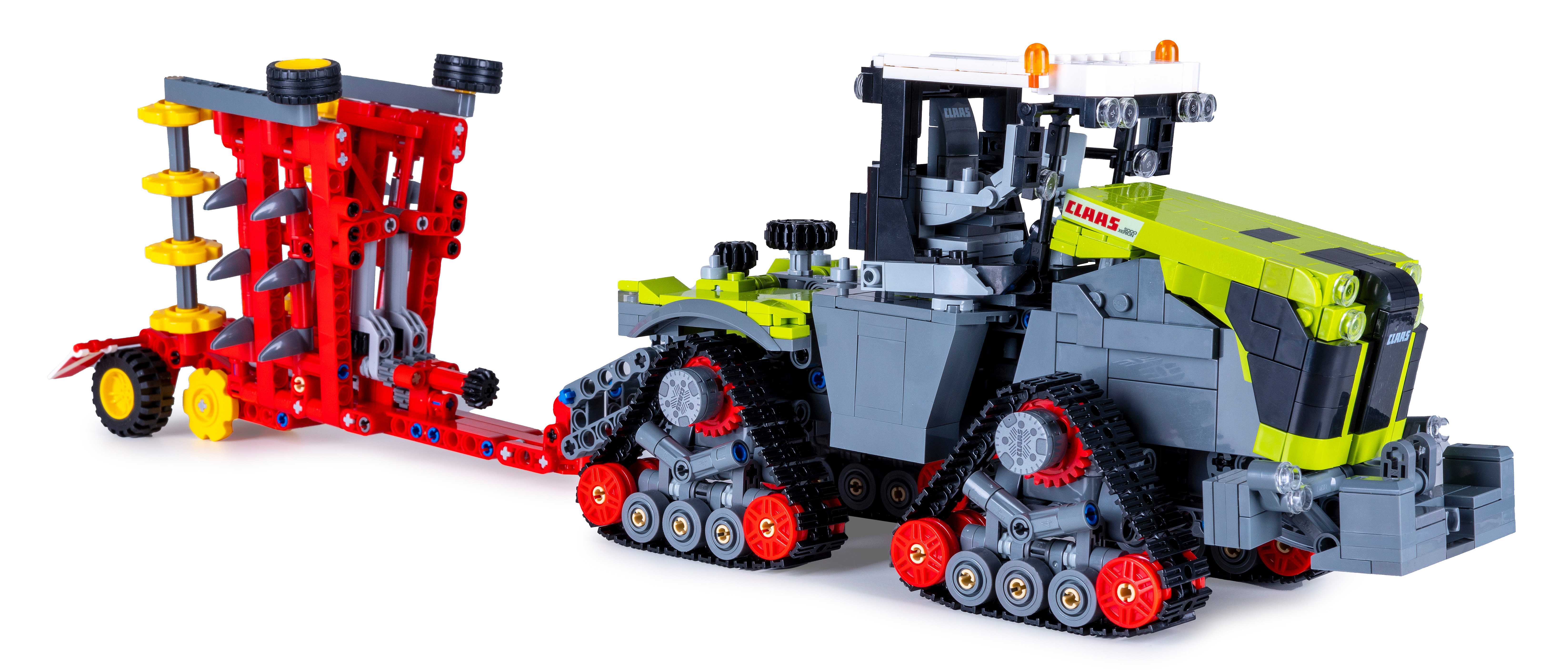 Ein Claas Lego-Traktor und Anhänger mit roten und gelben Elementen. Vor weißem Hintergrund, der Modelldetails zeigt.