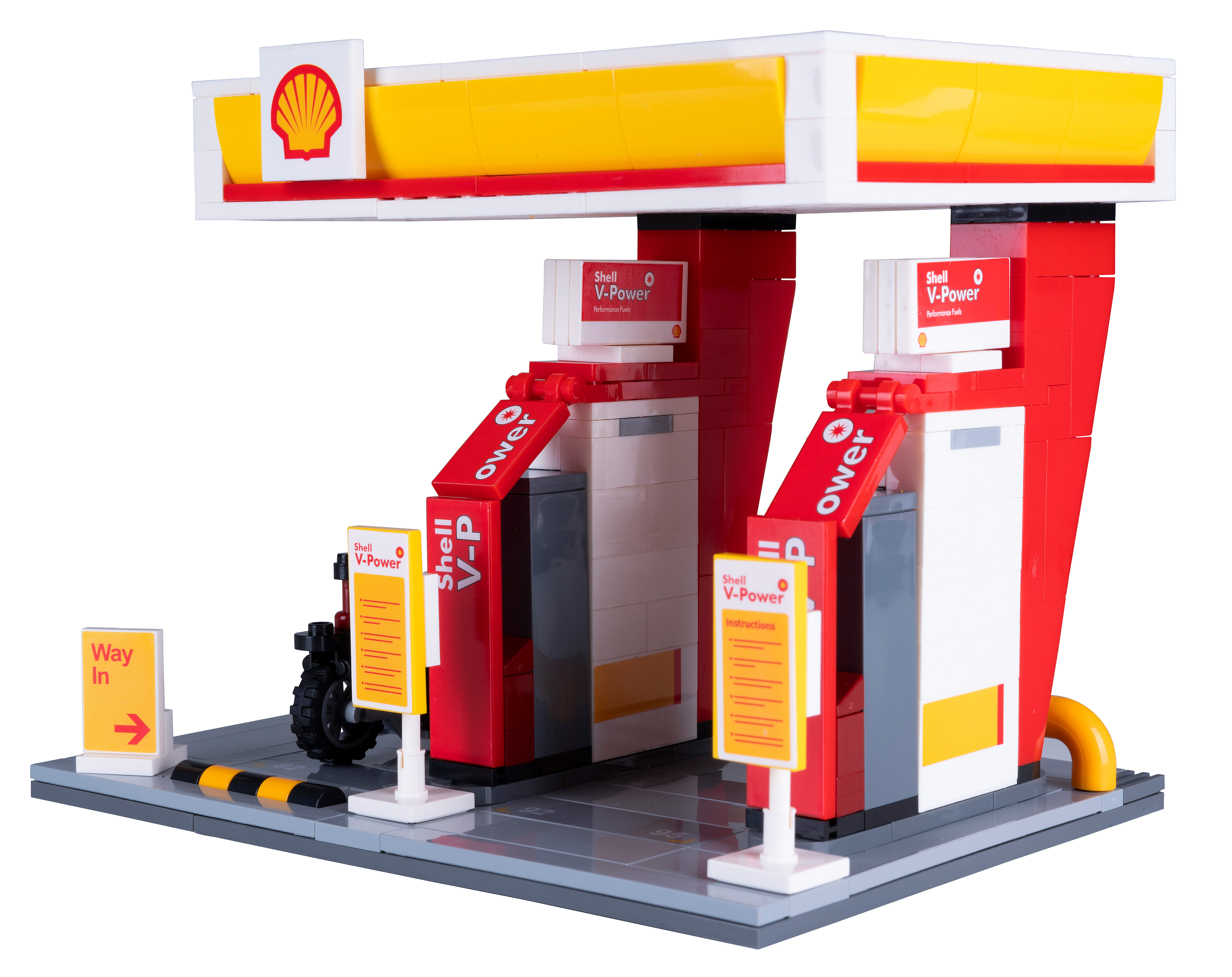 Eine Lego-Shell-Tankstelle. Sie hat ein Shell-Logo, Shell V-Power-Schilder und ein kleines Motorradmodell, alles auf grauer Basis.