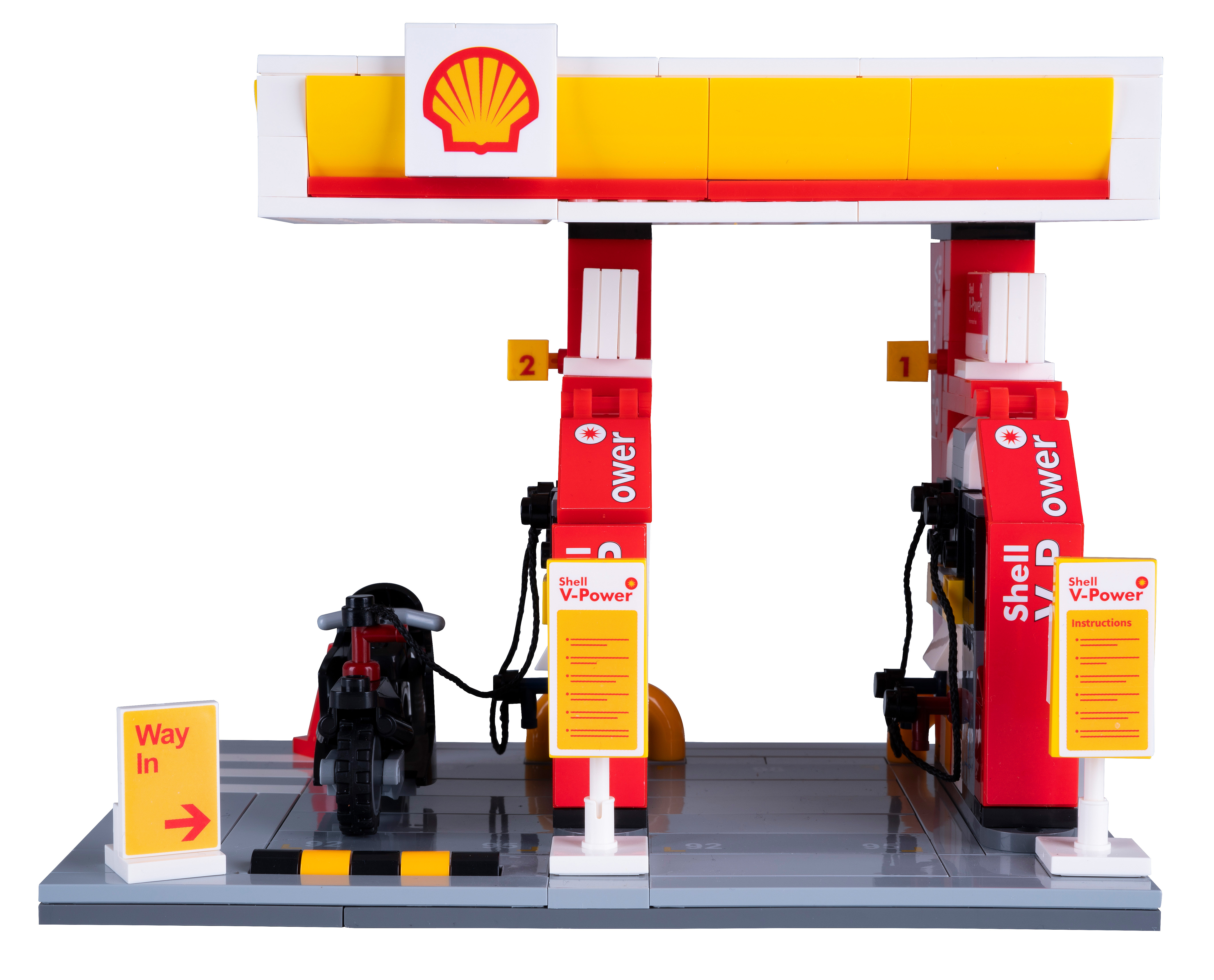 Eine LEGO Shell-Tankstelle mit Motorrad. Die Tankstelle ist rot und gelb. Ein Schild sagt "Way In".