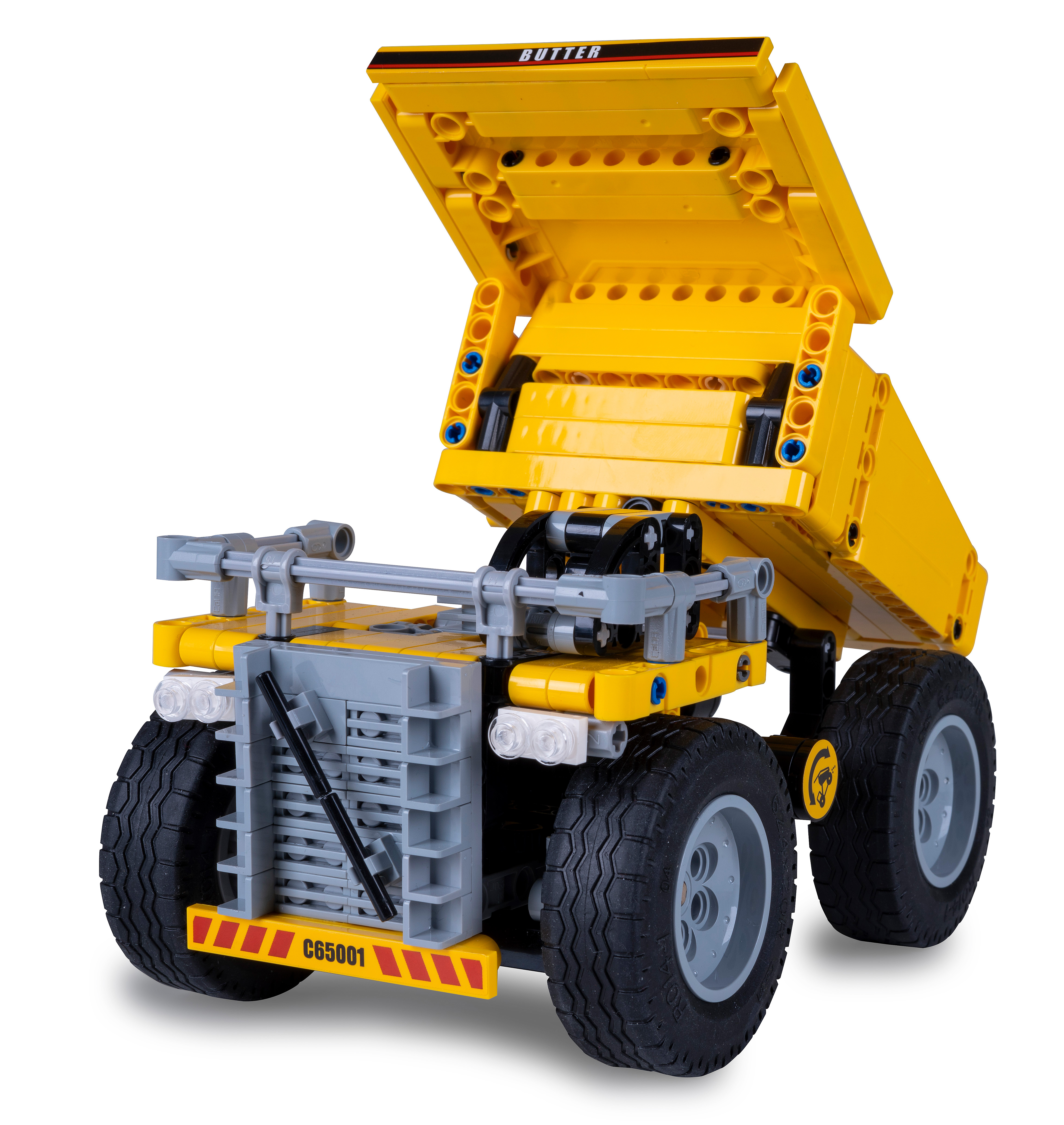 Ein gelb-graues Lego-Muldenkipper-Modell mit angehobenem Auflieger. Der Lkw steht auf einer weißen Oberfläche.