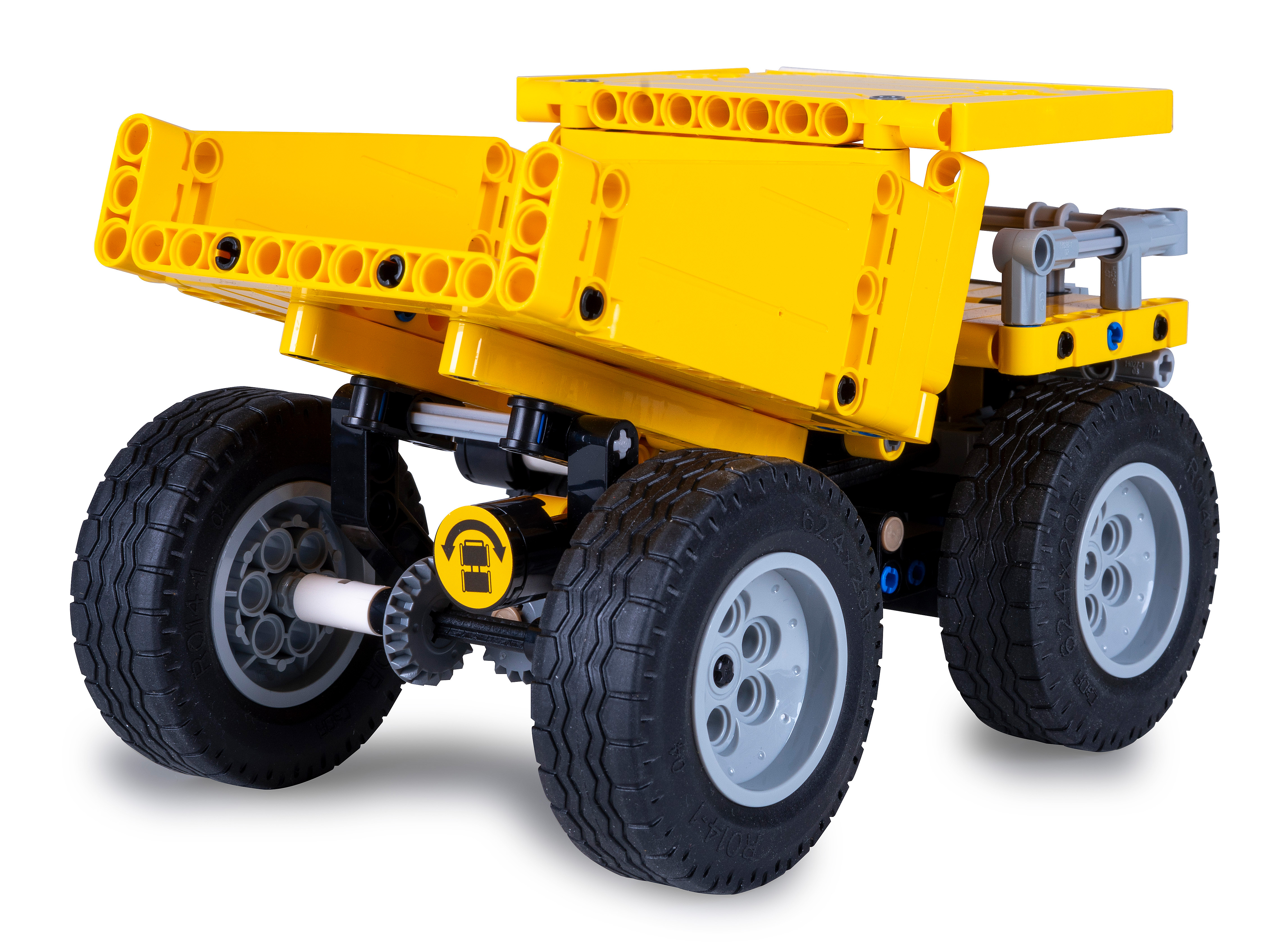 Ein gelber Lego-LKW mit schwarzen Rädern, grauen Felgen und einer kippbaren Ladefläche. Der Hintergrund ist weiß.