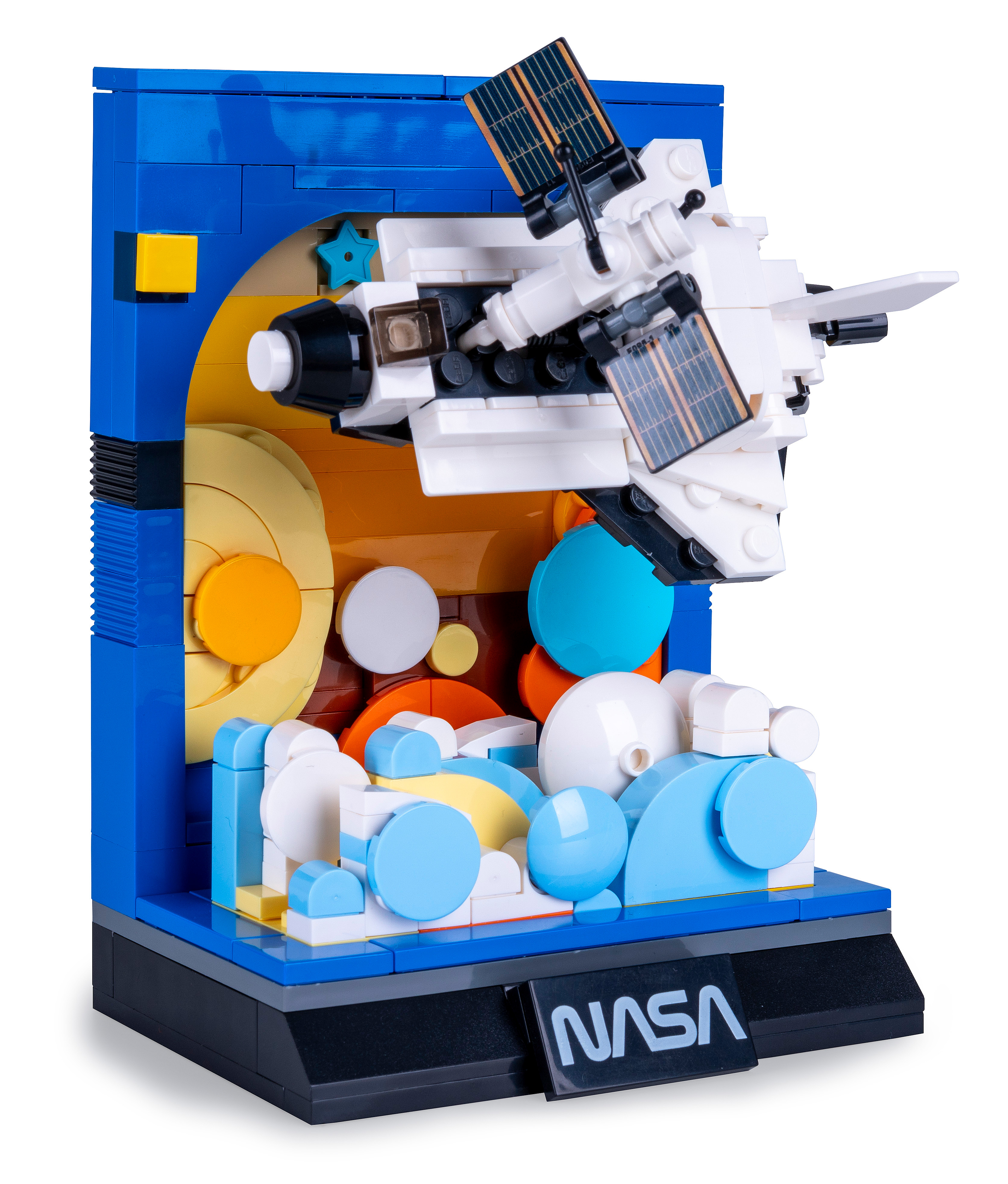 Ein Lego-Modell eines Raumschiffs mit Sonnenkollektoren, vor blau-orangem Hintergrund, auf einer Basis mit NASA-Logo.