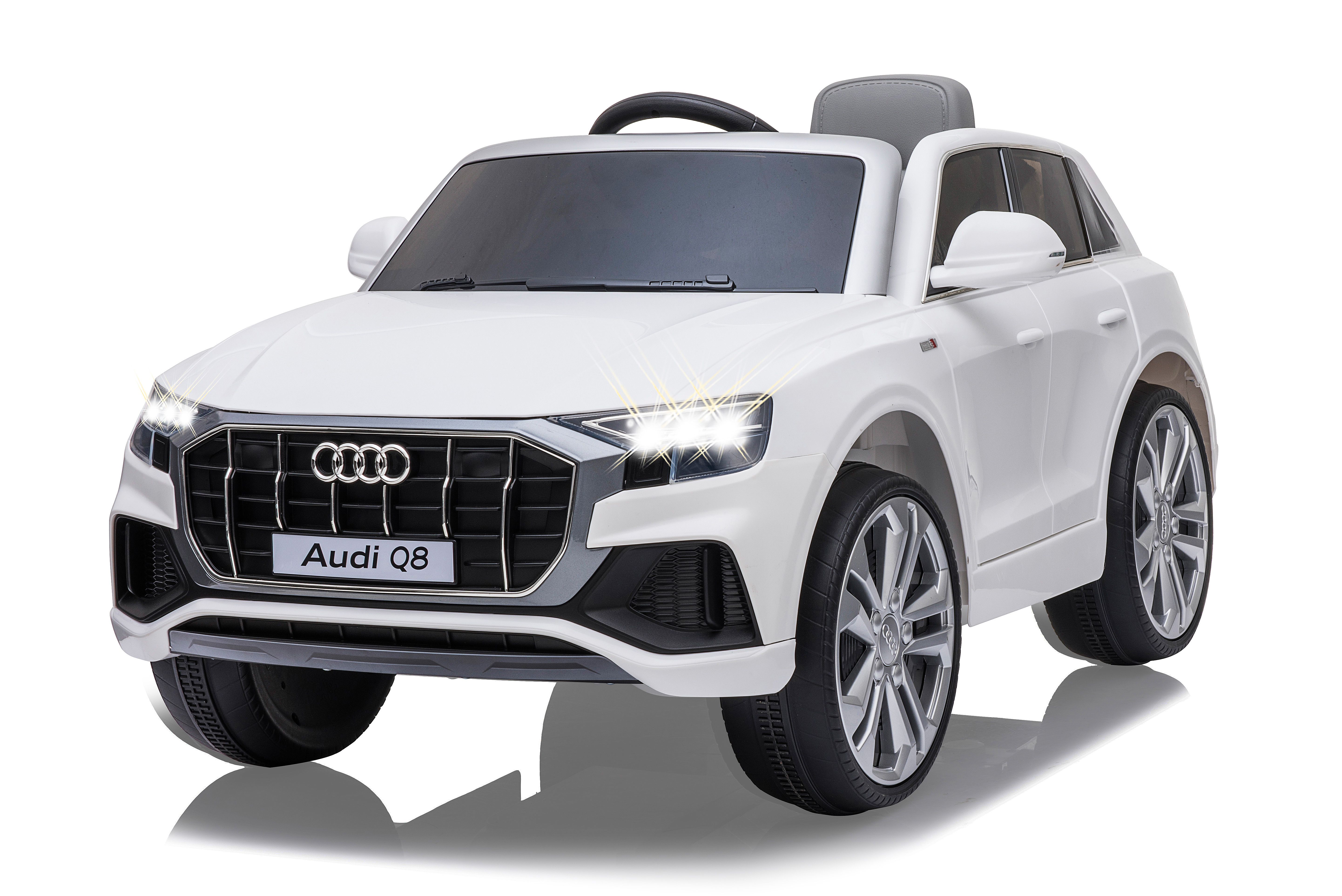 Ein weißes Audi Q8-Spielzeugauto. Es steht auf einer weißen Oberfläche. Die Scheinwerfer sind eingeschaltet. Das Auto hat ein schwarzes Lenkrad.