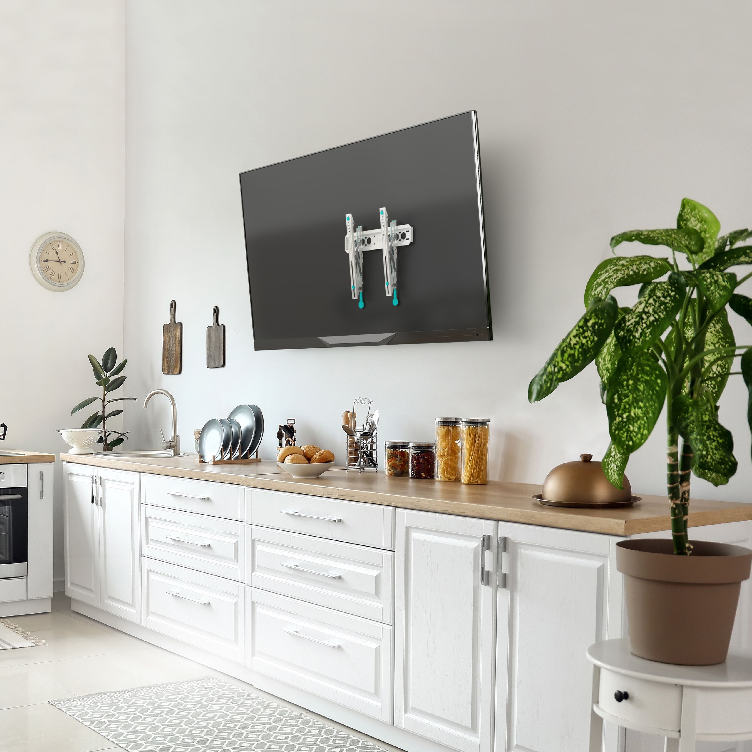 Kuchnia z telewizorem na ścianie. Szafki, talerze, rośliny i produkty spożywcze są widoczne na blacie.