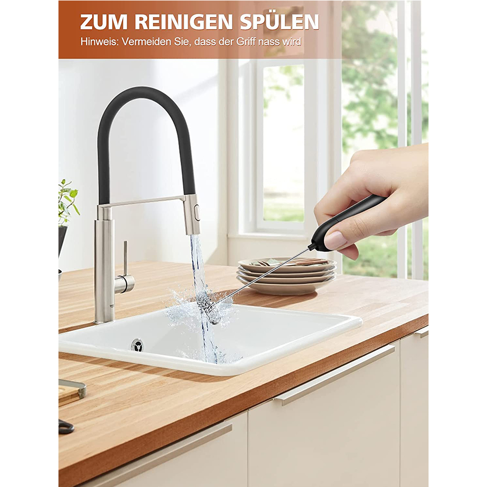 Eine Hand hält einen schwarzen Aufschäumer in einem weißen Waschbecken mit fließendem Wasser. Ein silberner Wasserhahn und eine Holz-Arbeitsplatte sind ebenfalls zu sehen.