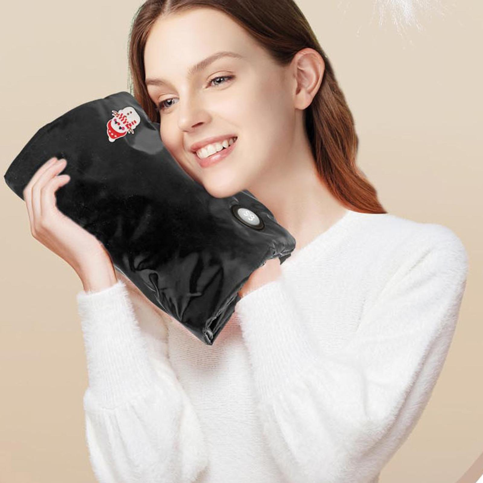 Frau hält einen schwarzen Handwärmer. Er hat einen Knopf und ein kleines Santa Claus-Symbol. Sie trägt einen weißen Pullover.