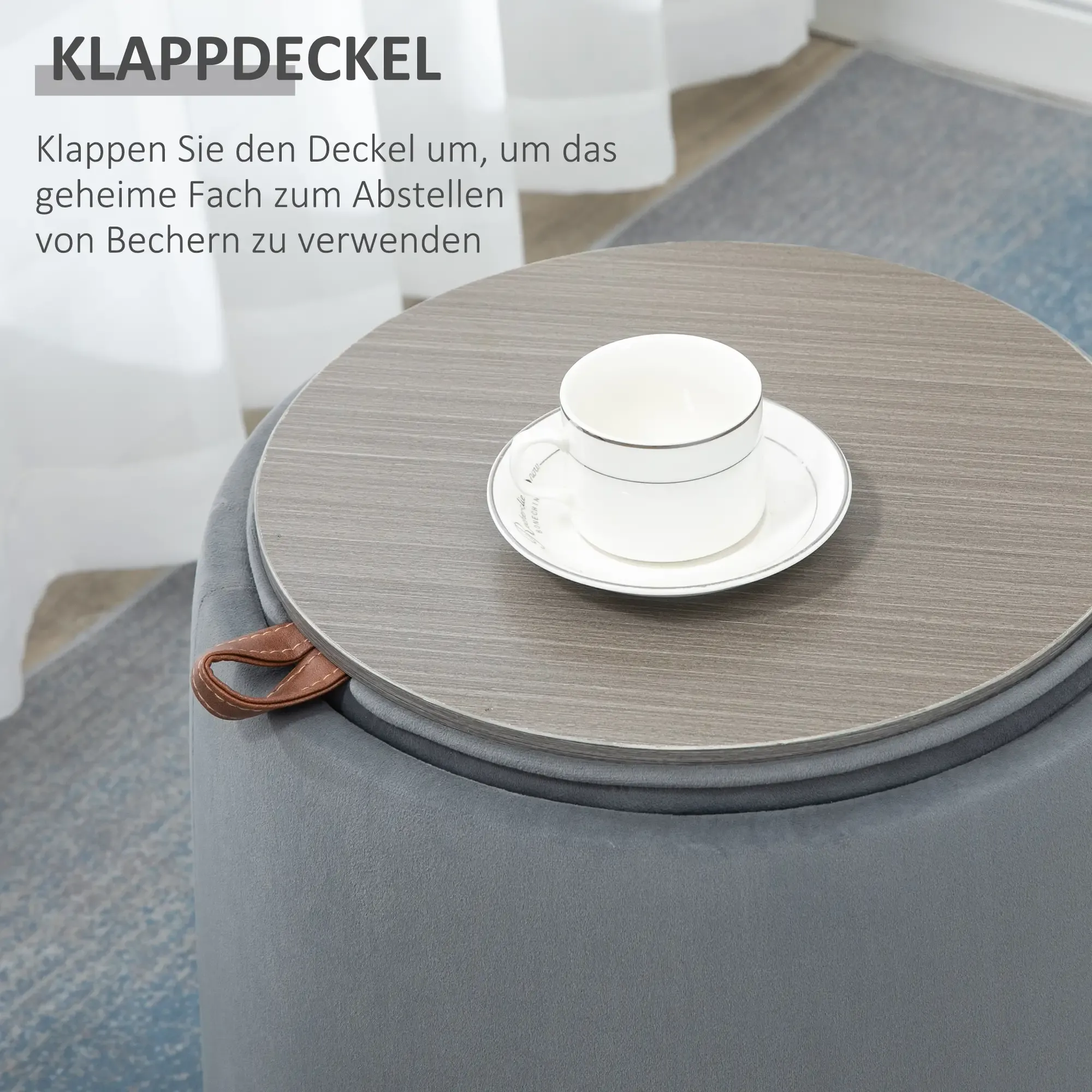 Ein runder grauer Hocker mit Holzplatte und Tasse auf Untertasse. Seitlich ist ein Ledergriff zu sehen.