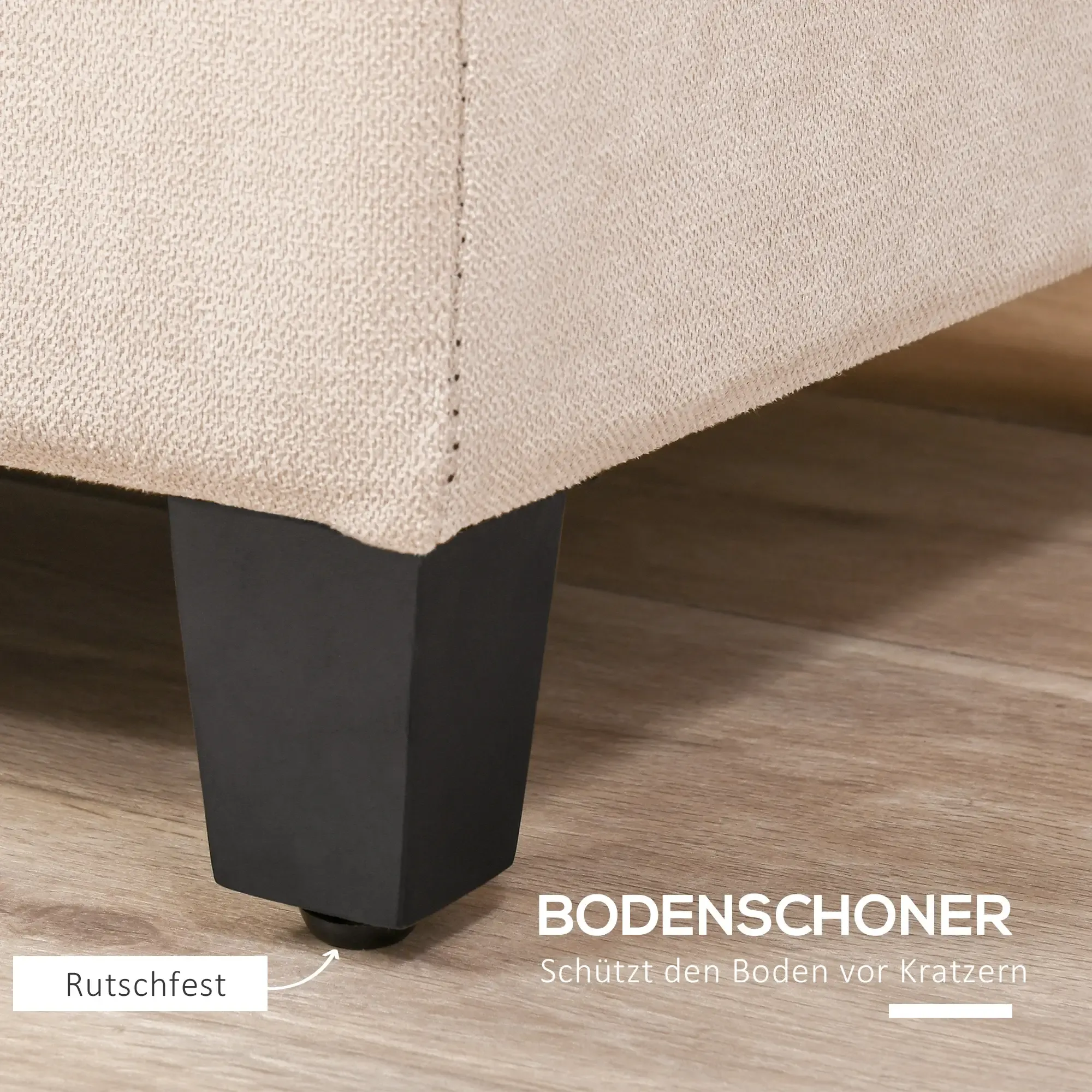 Nahaufnahme einer beigen Stoffecke mit schwarzem Bein. Das Bein hat einen Gummifuß auf einem Holzboden.