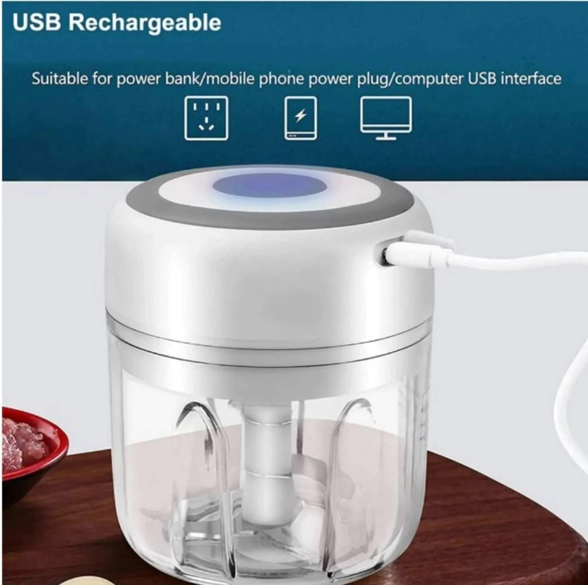 Ein weißer und grauer Mini-Zerkleinerer mit einem transparenten Behälter. Enthält ein USB-Kabel. Der Hintergrund zeigt Text.