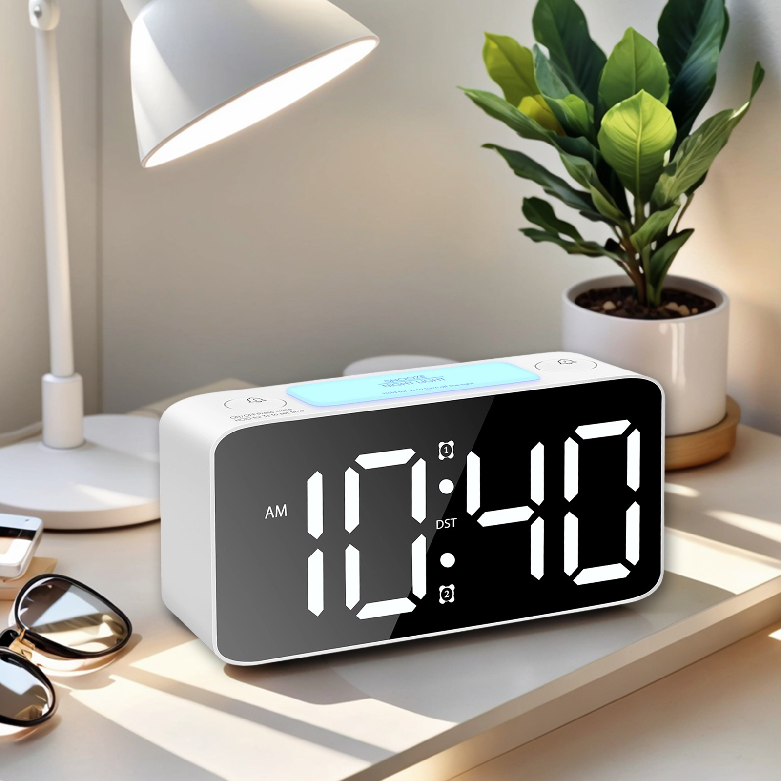 Ein weißer digitaler Wecker zeigt 10:40 Uhr an. Eine Schreibtischlampe und eine Topfpflanze sind ebenfalls sichtbar.