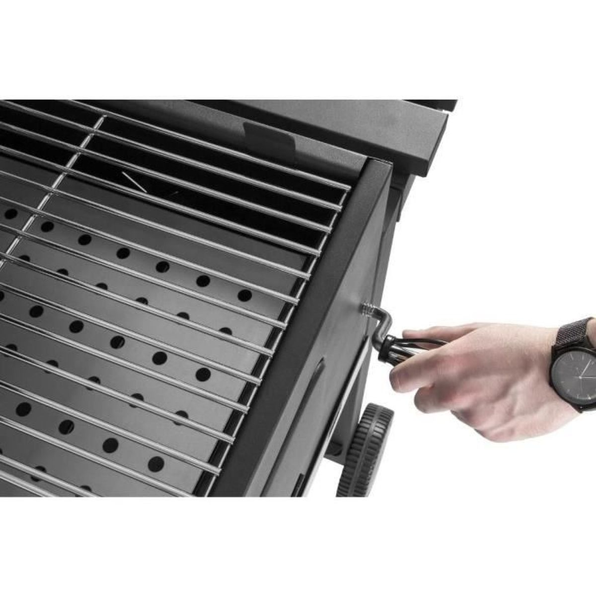 Eine Hand dreht einen Griff an einem schwarzen Grill. Eine Uhr befindet sich am Handgelenk der Person. Der Grill hat einen Metallrost.