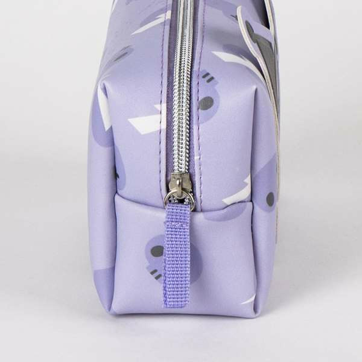 A lavender cosmetic bag with a silver zipper. The bag has a pattern of white shapes and dark gray spots. The pull tab is also lavender.