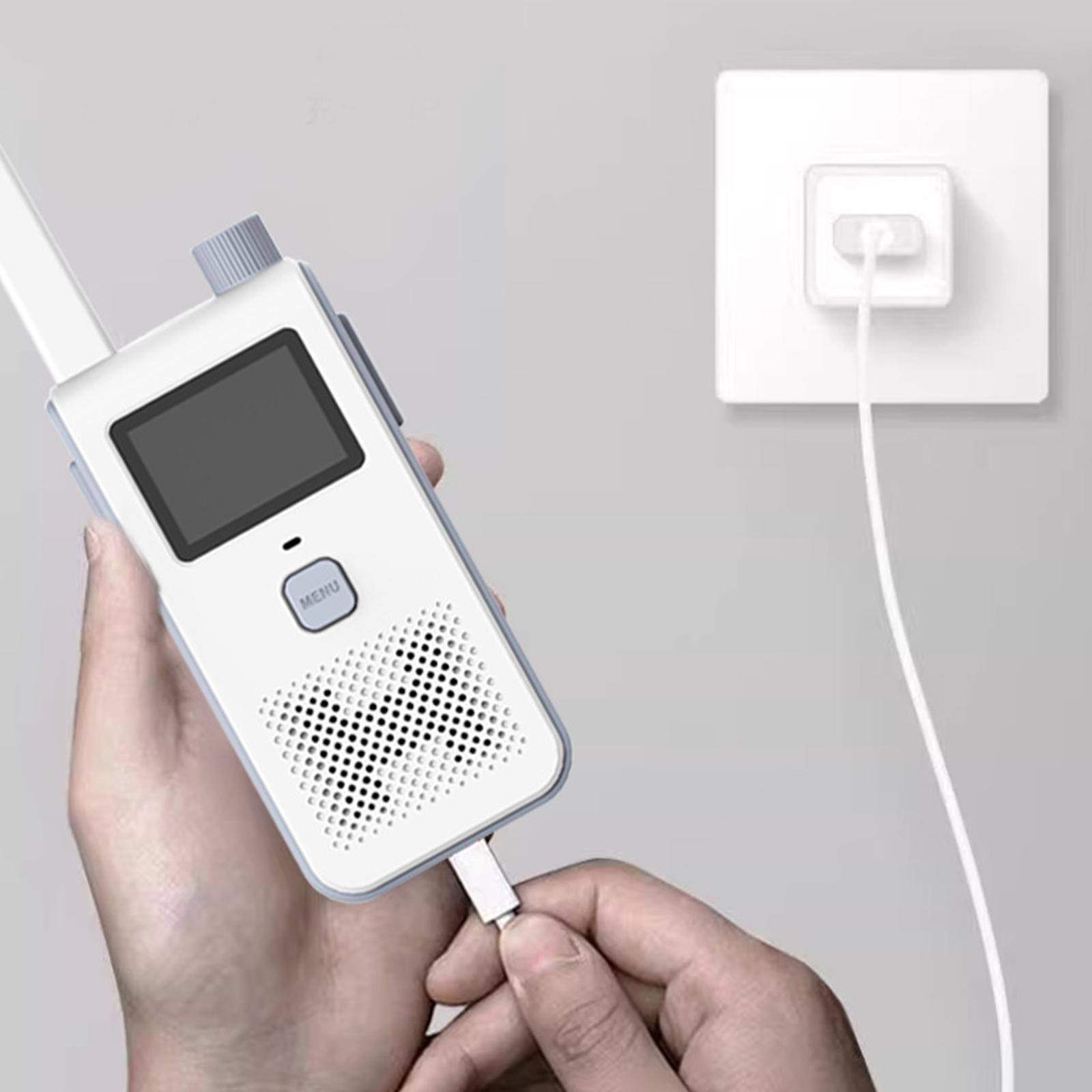 Eine Person hält ein weißes Walkie-Talkie und lädt es mit einem USB-Kabel auf. Im Hintergrund befindet sich eine Steckdose.