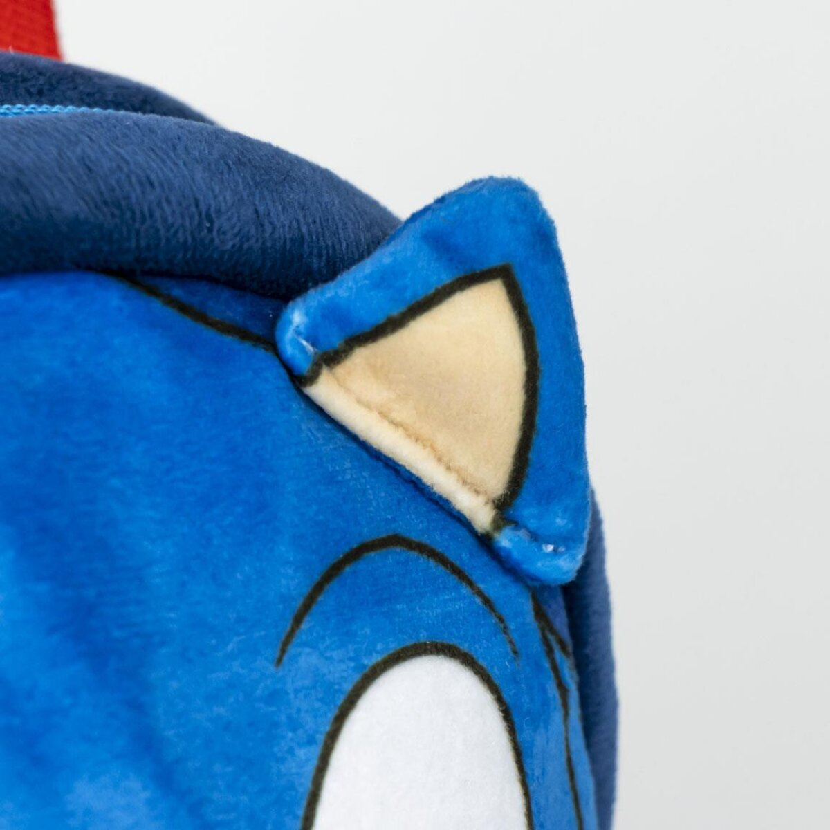Primer plano de una oreja de peluche azul con interior beige y contorno negro. Parte de una cabeza azul es visible.