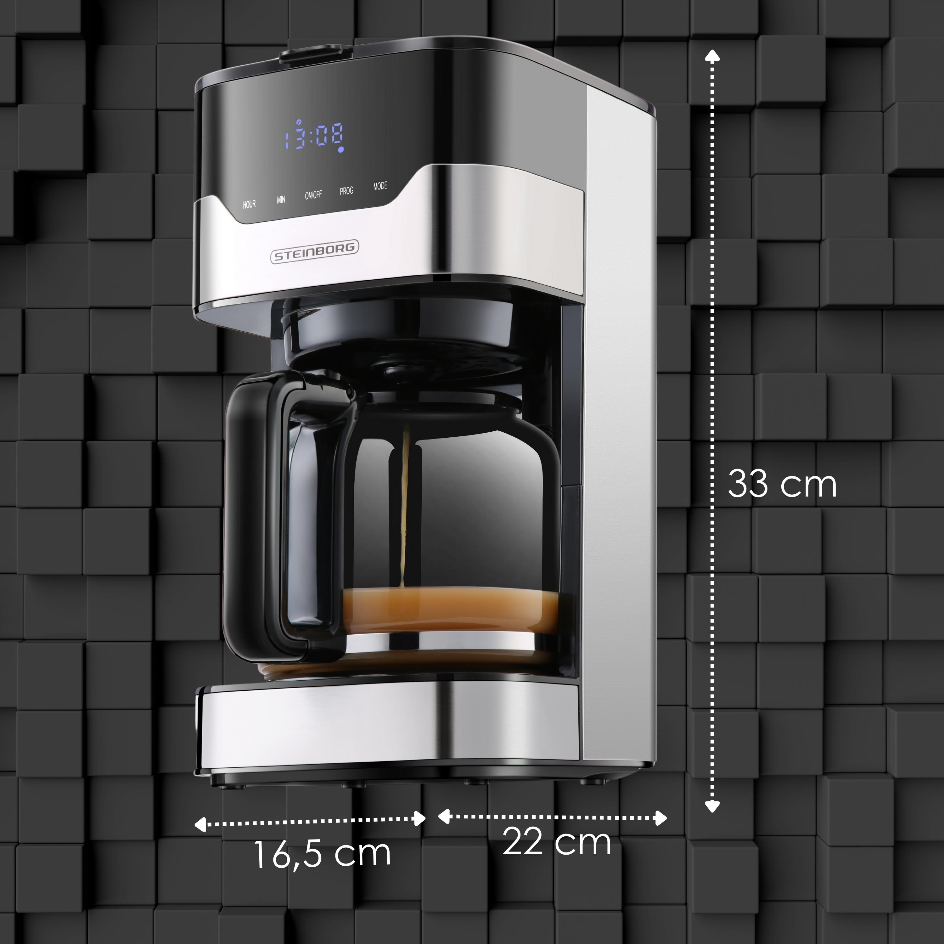 Ein schwarzer und silberner Kaffeeautomat mit Maßangaben. Der Hintergrund ist eine strukturierte Wand aus schwarzen Würfeln.