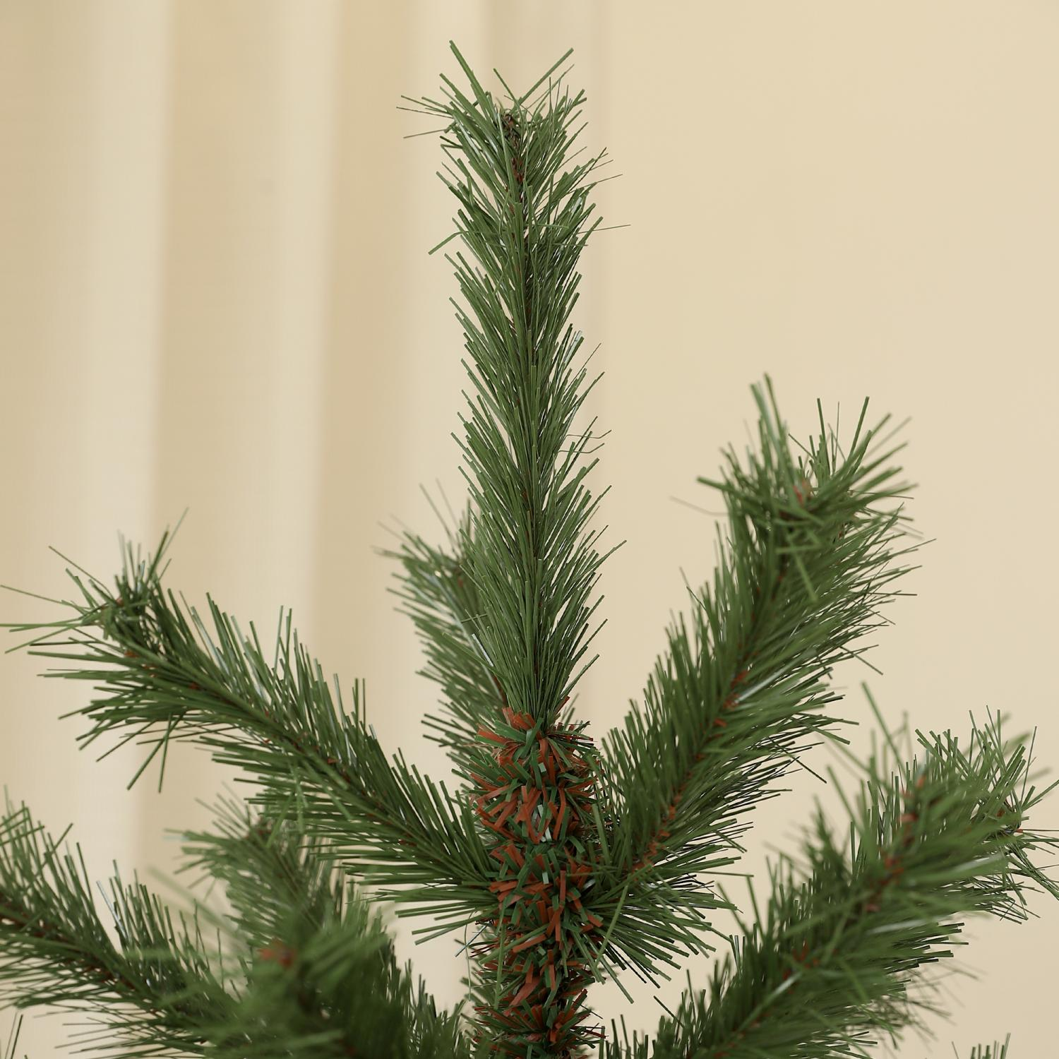 Nahaufnahme eines grünen künstlichen Weihnachtsbaumzweigs. Nadeln sind sichtbar. Der Hintergrund ist ein einfacher beiger Vorhang.