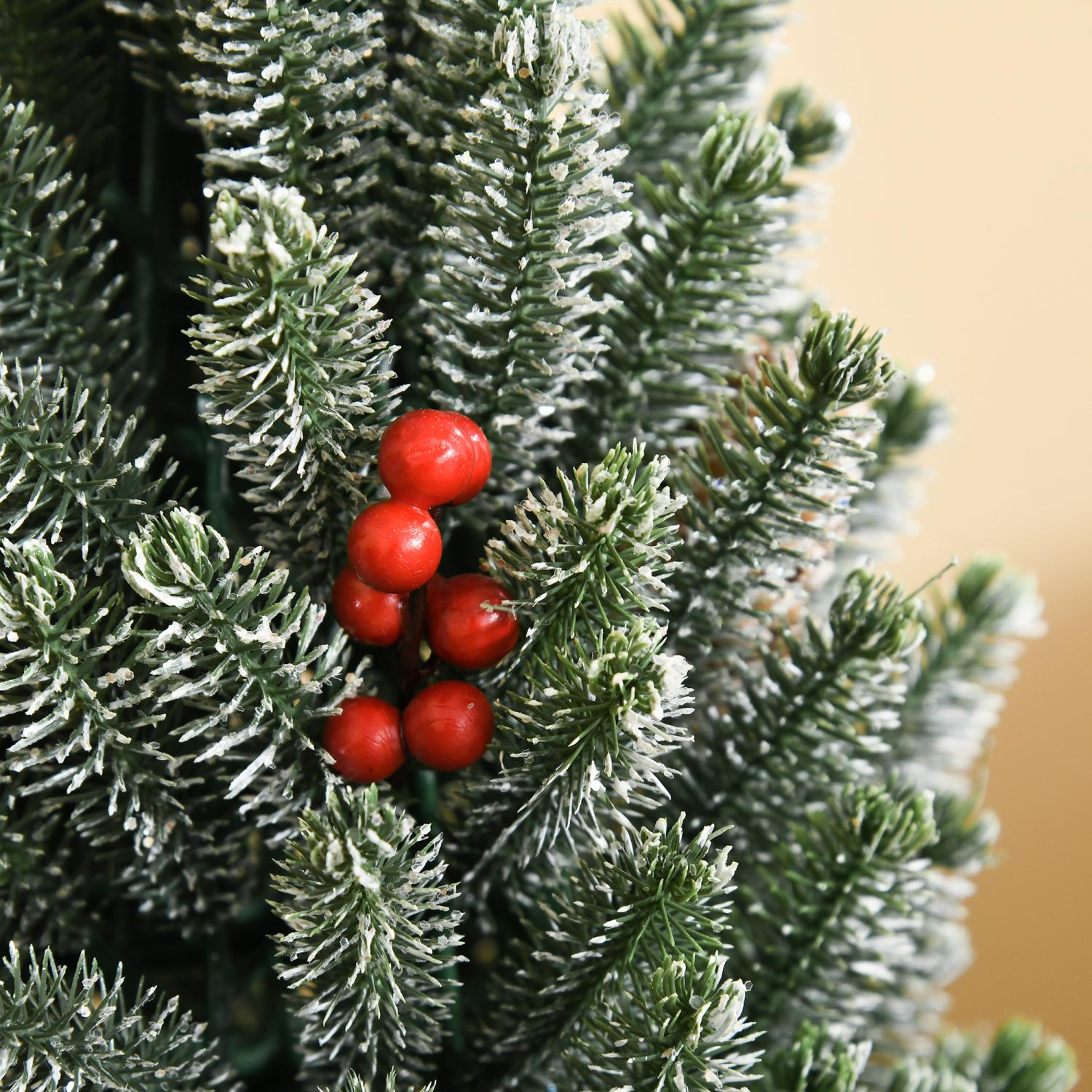 Nahaufnahme eines Weihnachtsbaumzweigs mit grünen Nadeln, weißen Akzenten und roten Beeren. Der Hintergrund ist verschwommen beige.
