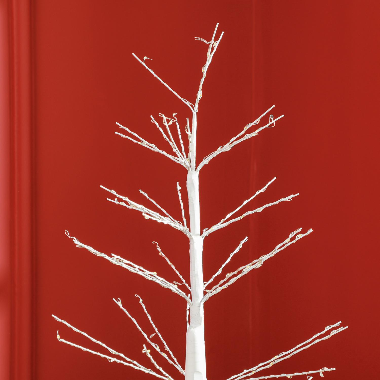 Ein weißer, blattloser Baum mit winzigen Lichtern vor einem leuchtend roten Hintergrund. Die Äste des Baumes erstrecken sich nach außen.