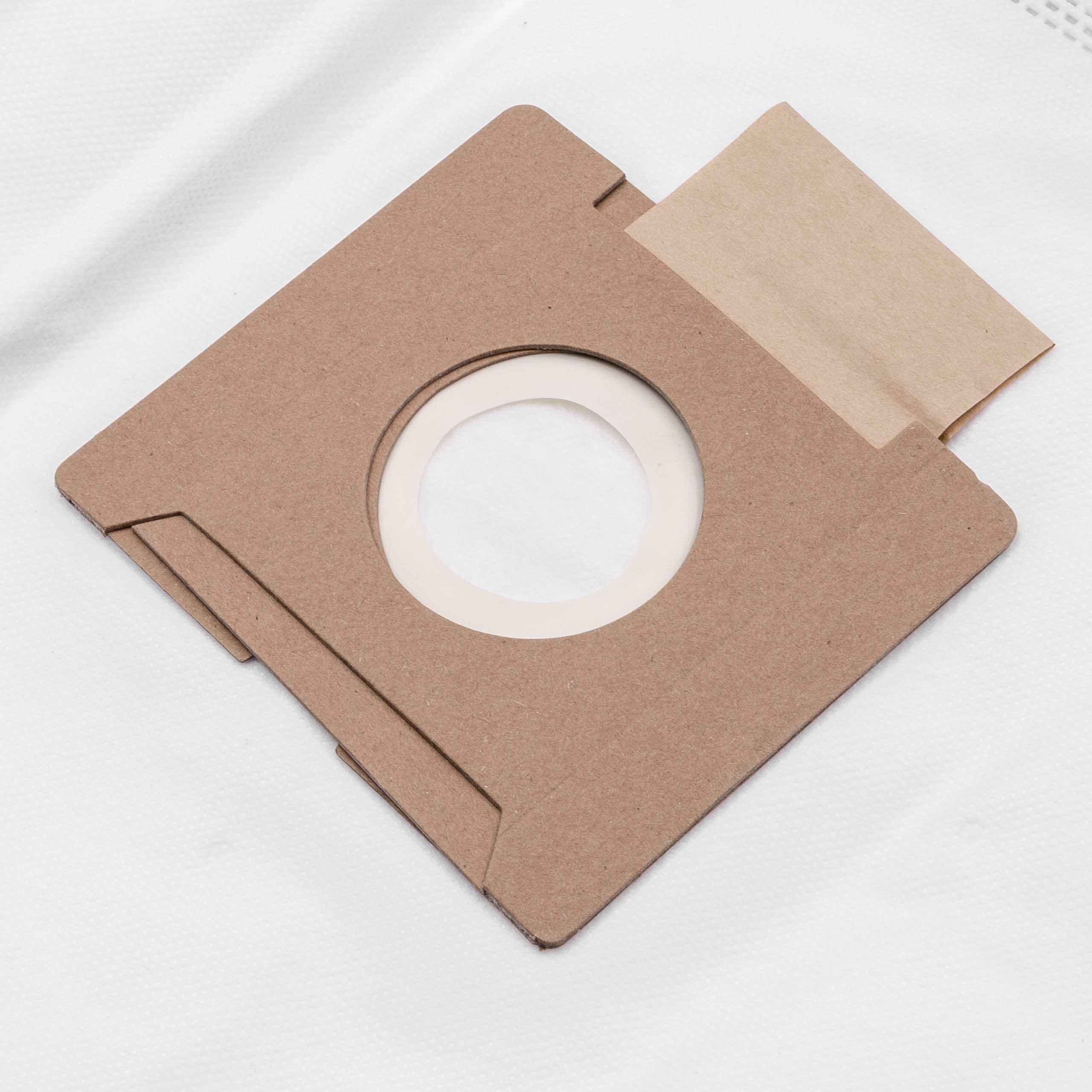 Ein brauner Staubsaugerbeutel aus Papier mit einer weißen, kreisförmigen Öffnung liegt auf einer weißen, strukturierten Oberfläche.