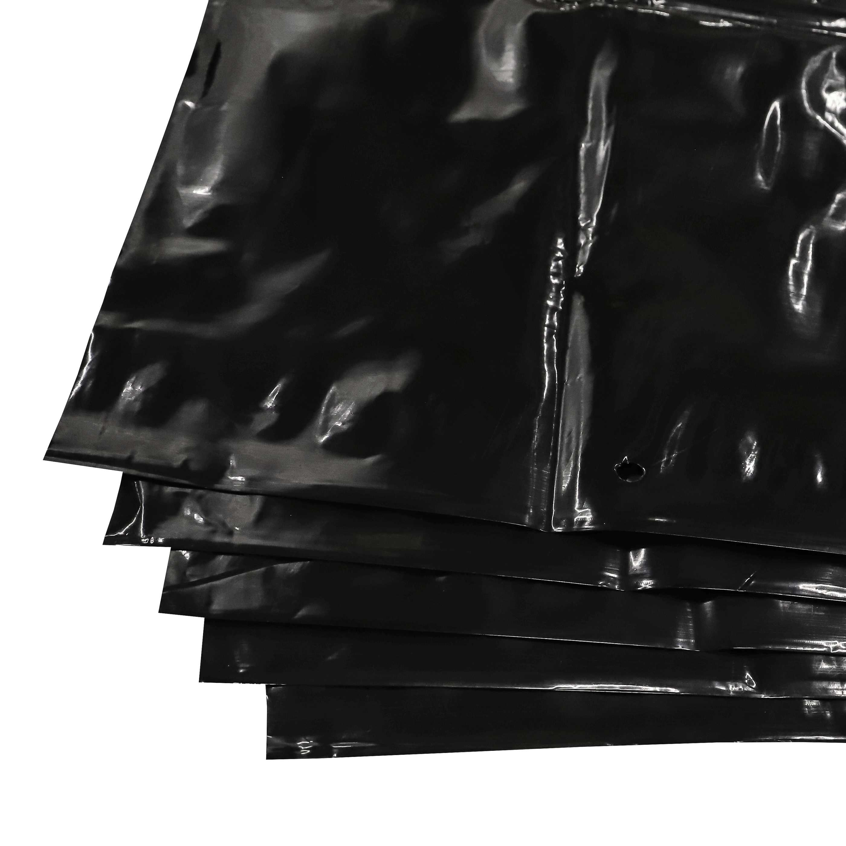 Nahaufnahme mehrerer schwarzer Plastiktüten, die sich auf weißem Hintergrund überlappen. Die Taschen sind glänzend.