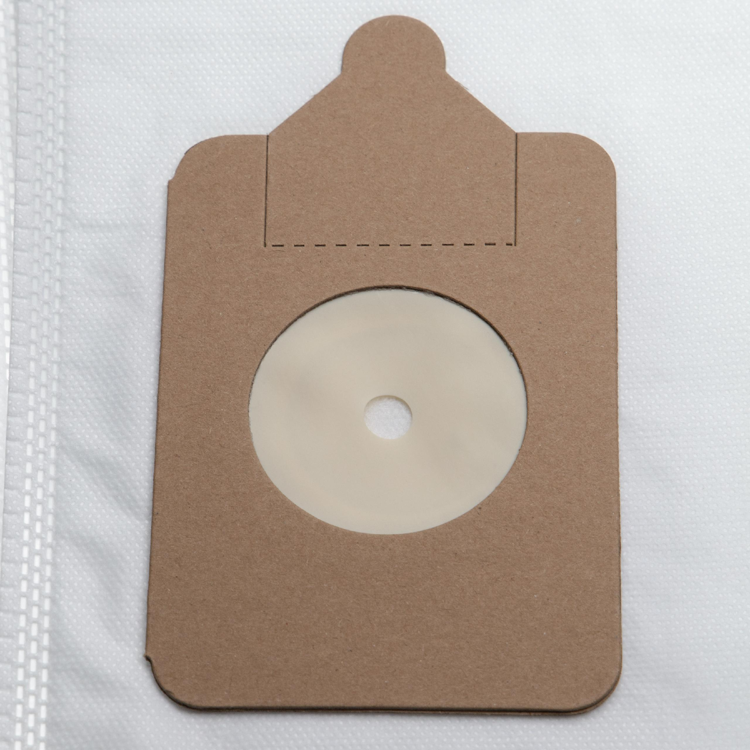 Ein brauner Papier-Staubsaugerbeutel mit einem zentralen beigen Filter und einem kleinen Loch in der Mitte, vor weißem Hintergrund.
