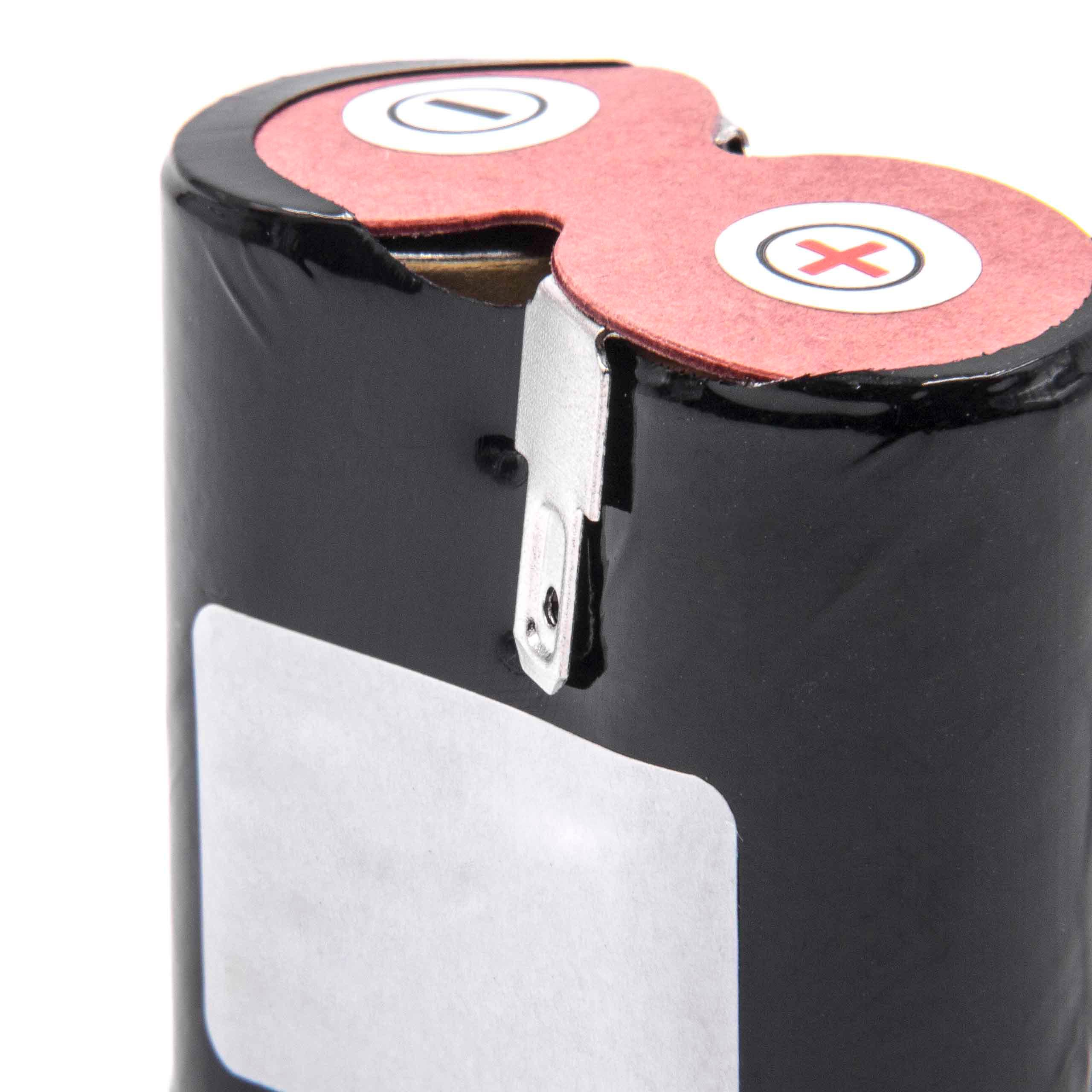 Nahaufnahme einer schwarzen Batterie mit roter Oberseite. Eine Metalllasche ist sichtbar. Die Oberseite hat weiße Aufkleber mit Symbolen.