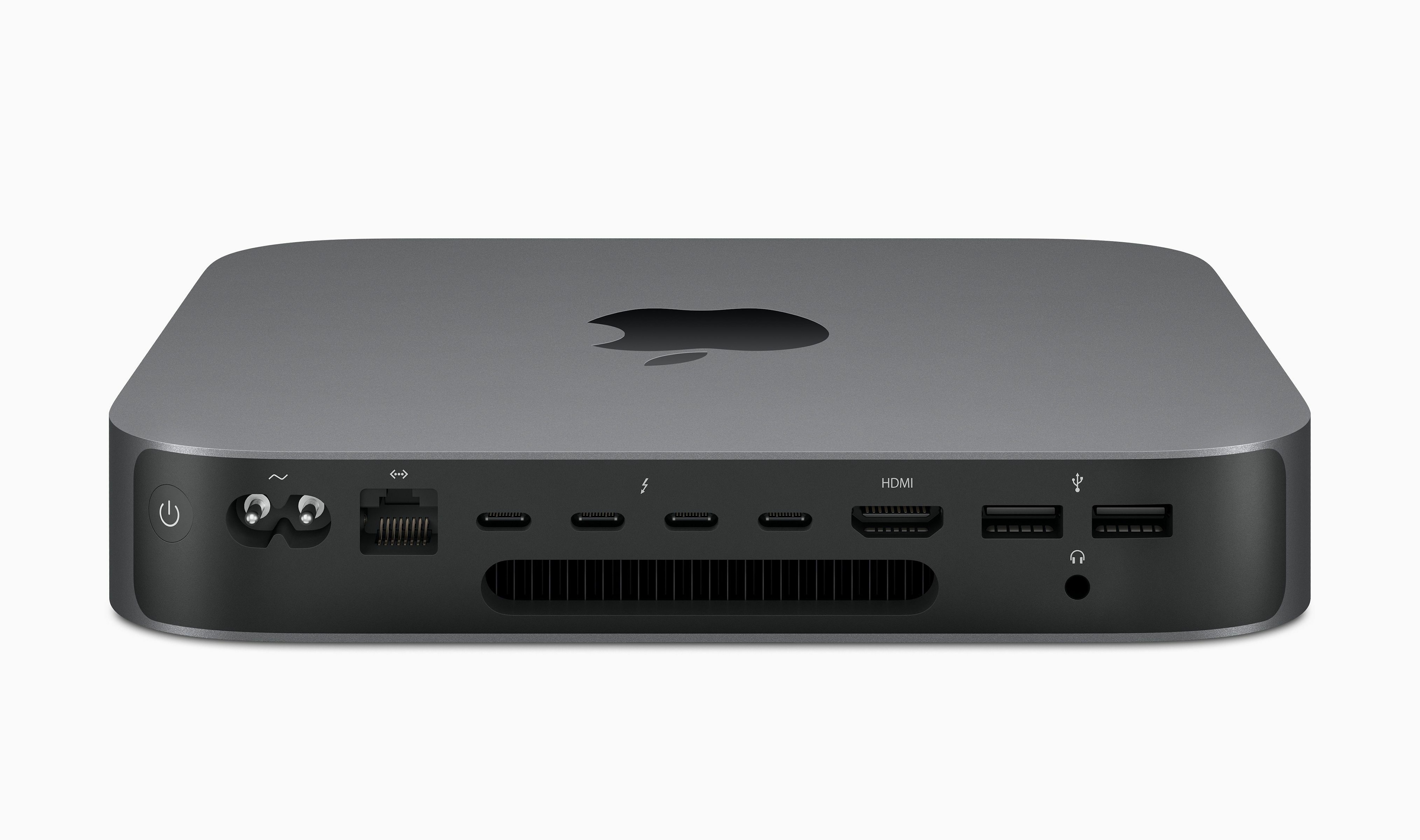 Srebrny Mac Mini na białym tle. Z przodu znajdują się porty i przycisk zasilania. Logo Apple na górze.