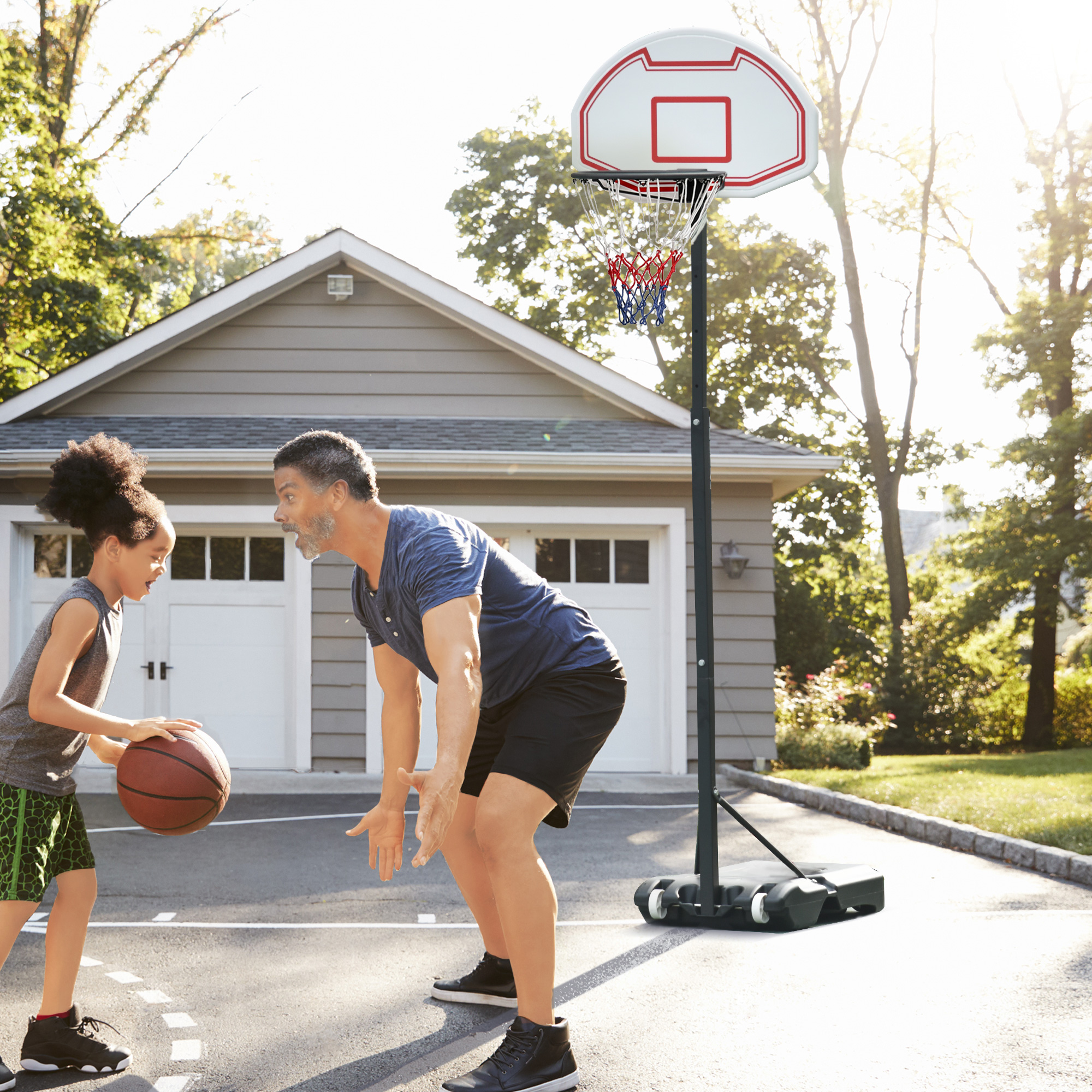 Un niño y un hombre juegan baloncesto al aire libre. Hay un aro de baloncesto en el fondo. El niño sostiene la pelota.