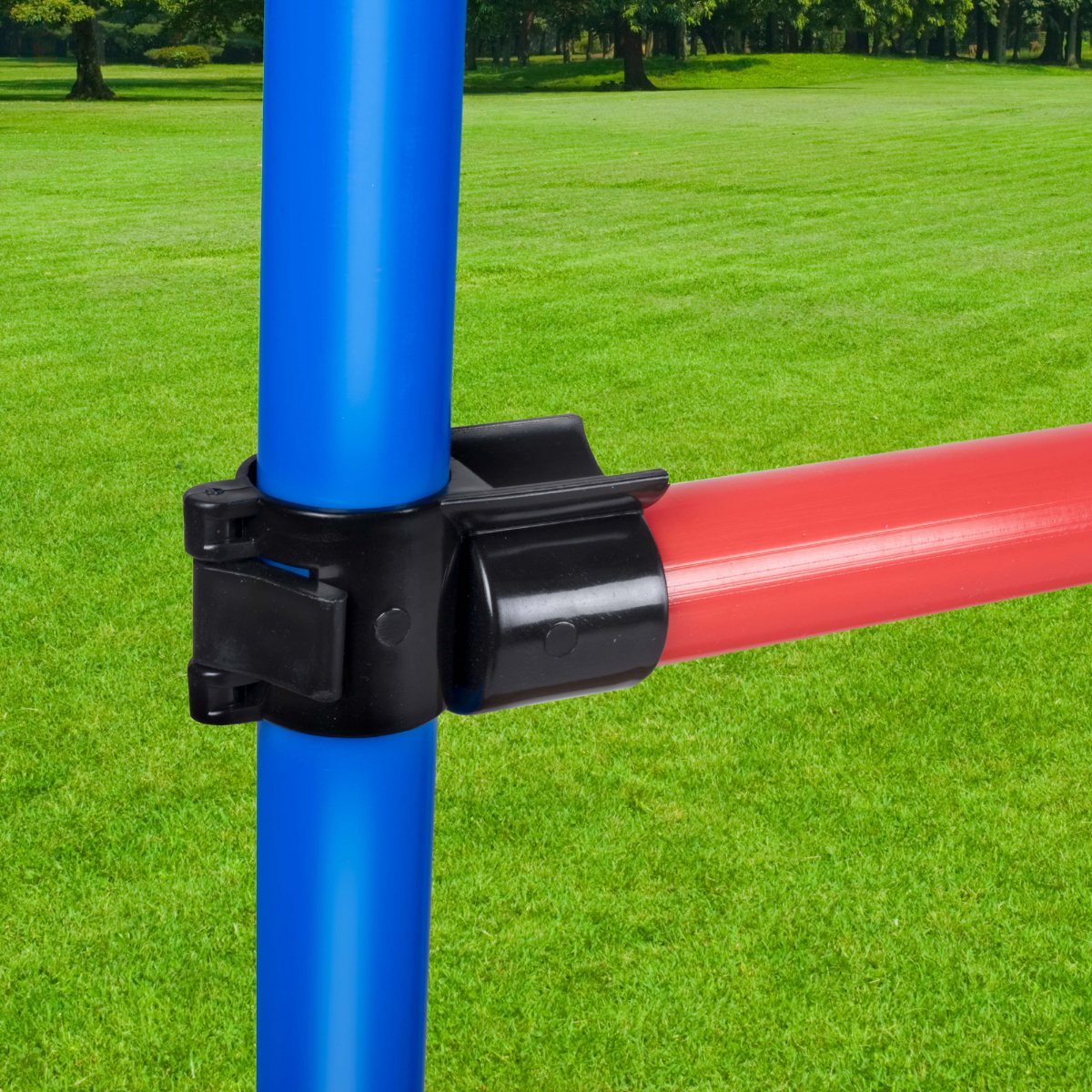 Un tubo verticale blu e un tubo orizzontale rosso sono collegati da un connettore in plastica nera, su uno sfondo erboso verde.